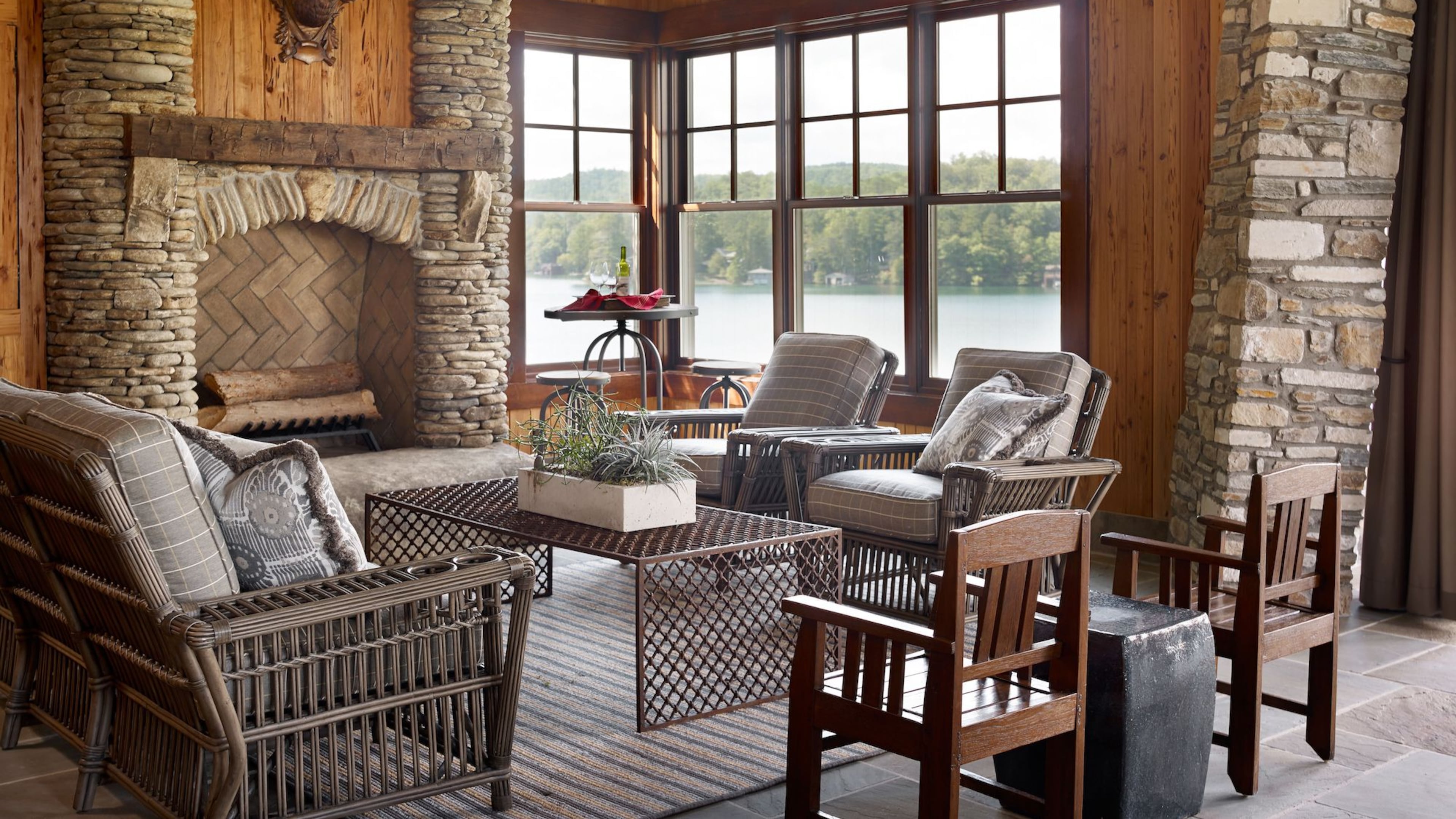 Wood, stone and a view of water and trees outside allow this indoor space from Carter Kay Interiors to embrace the outdoors. Courtesy of Carter Kay Interiors