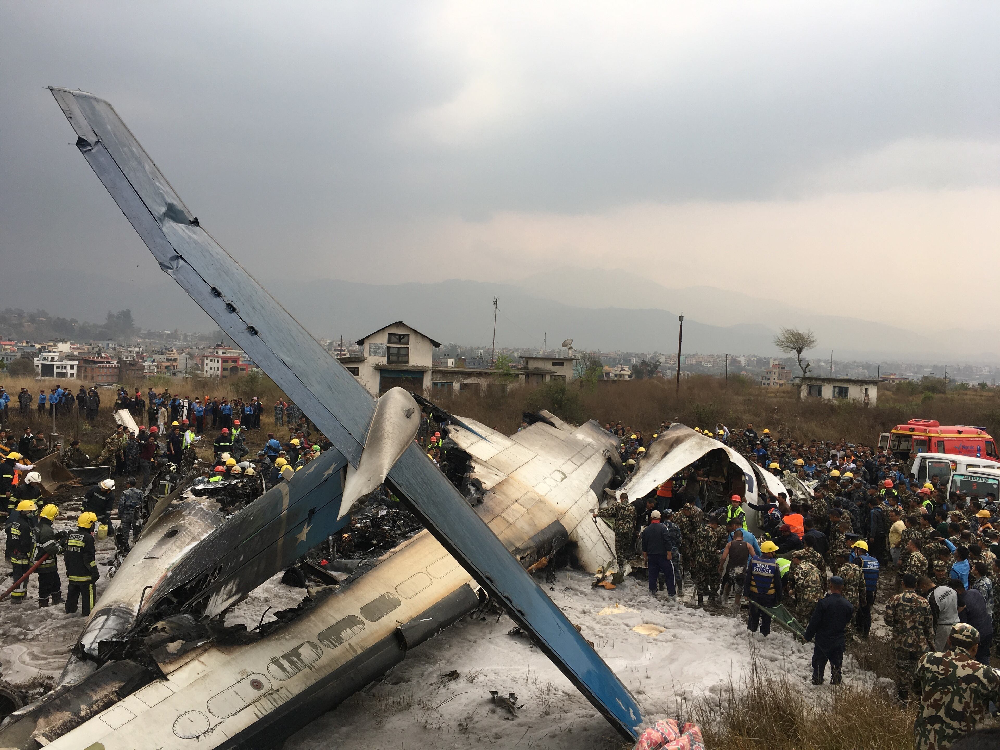 Nepalese rescuers stand near a passenger plane from Bangladesh that crashed at the airport in Kathmandu, Nepal, Monday, March 12, 2018. (AP Photo/Niranjan Shreshta)