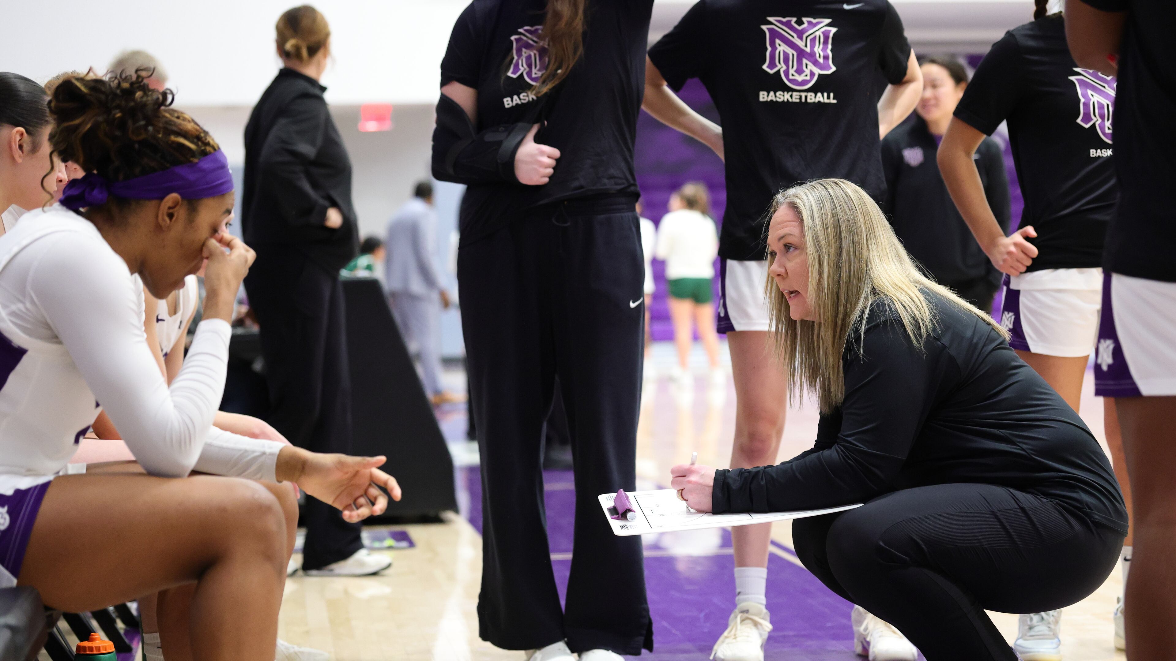 This photo provided by NYU Athletic Communications shows NYU coach Meg Barber, right, talking to players on her team Sunday, Feb. 1, 2026. (NYU Athletic Communications via AP)