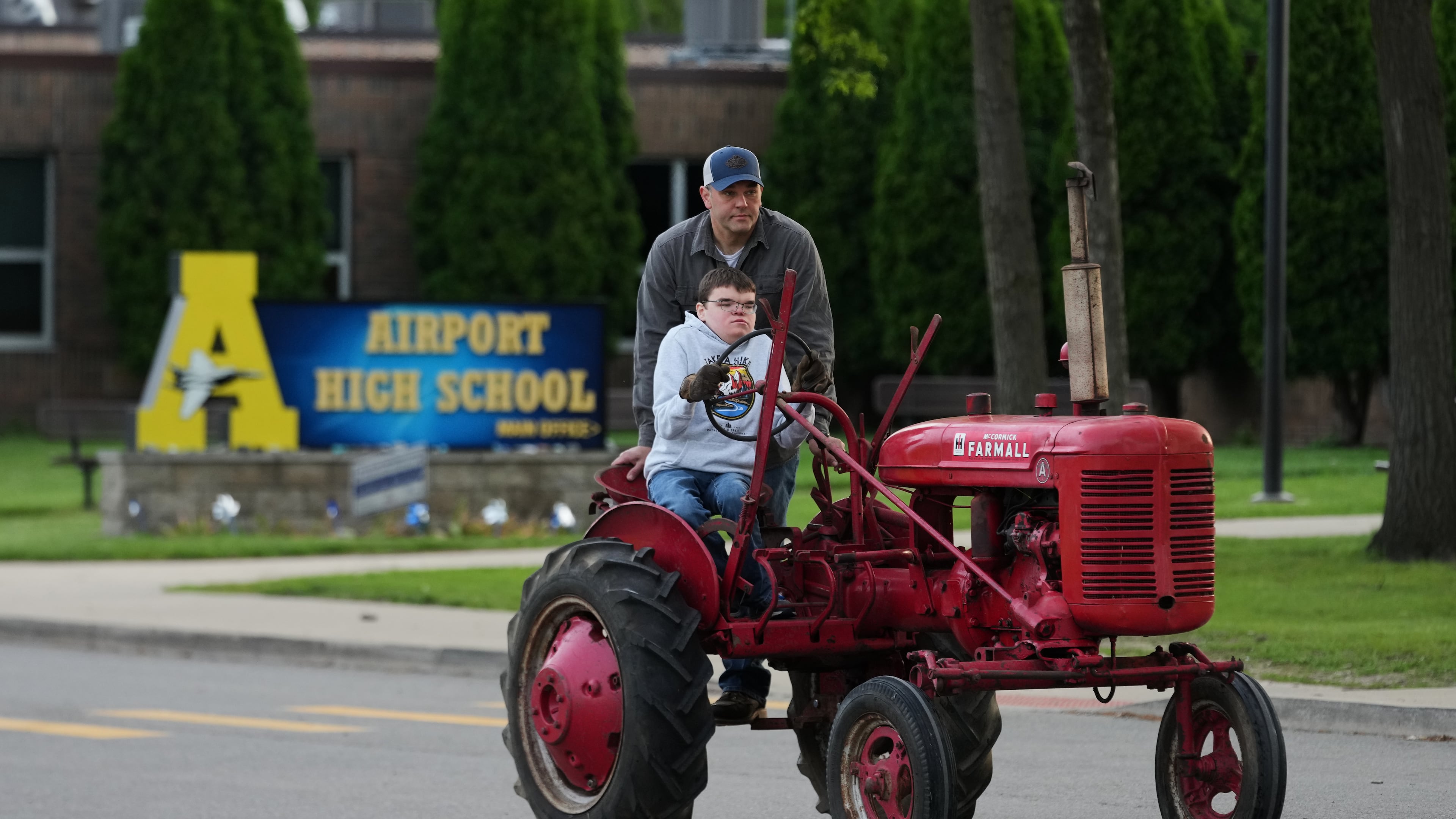 Austin Neddo drives a 1940 Farmall A tractor with his father Shay during Tractor Day for graduating seniors at Airport High School Friday, May 22, 2026, in Carleton, Mich. (AP Photo/Paul Sancya)