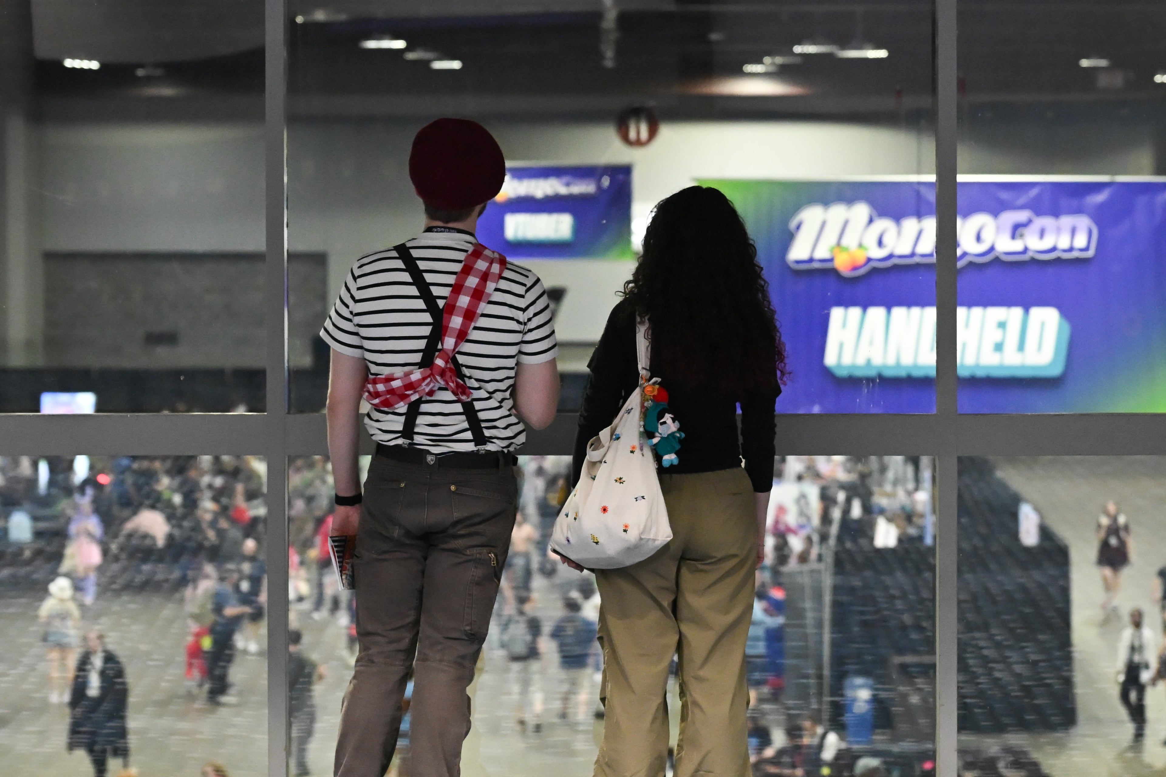 Two attendees watch the vendor hall during MomoCon at the Georgia World Congress Center in Atlanta on Friday, May 22, 2026. (Tyler Sun for the AJC)
