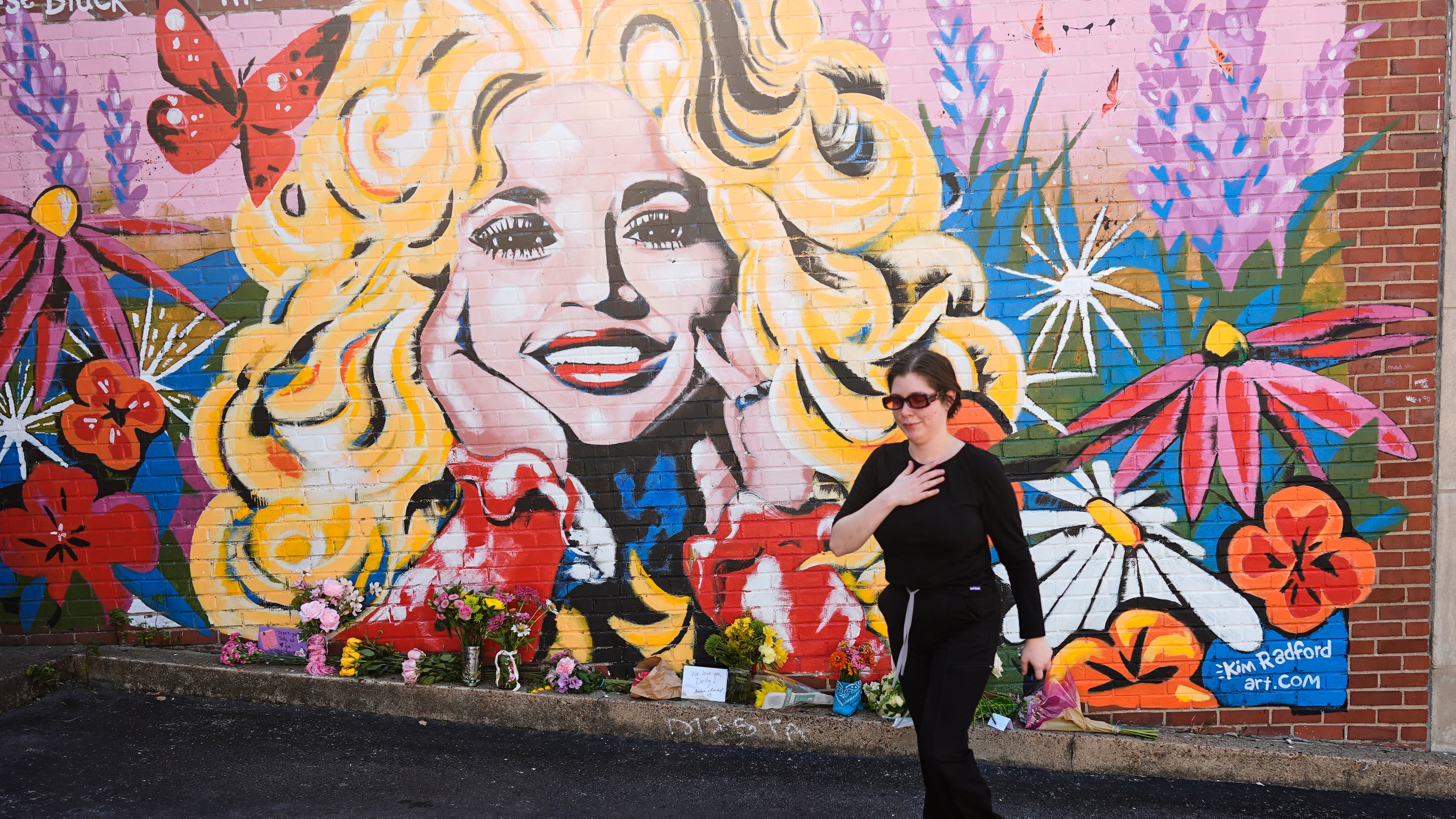 Katie Greene visits a mural of Dolly Parton on Tuesday, Aug. 25, 2026, in Nashville, Tenn. Parton did not like talking about her politics, but she spoke her values through her words and actions, AJC opinion editor David Plazas writes. (George Walker IV/AP)