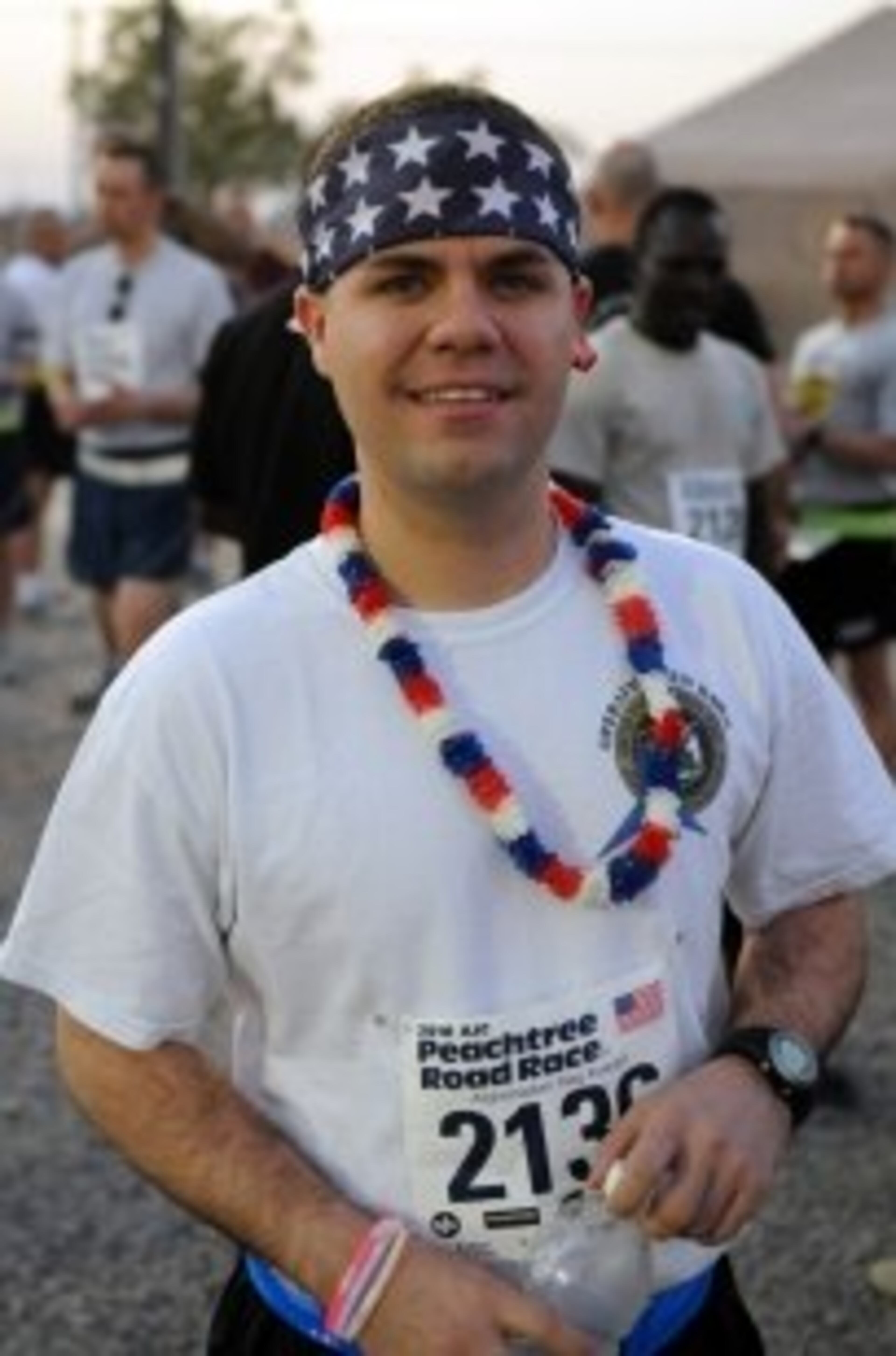 Staff Sgt. Jeremy Cooper, a Blountstown, Fla., native, assigned to Company C, Special Troops Battalion, United States Forces-Iraq, proudly displays the red, white and blue colors at the AJC Peachtree Road Race in Baghdad on July 4.