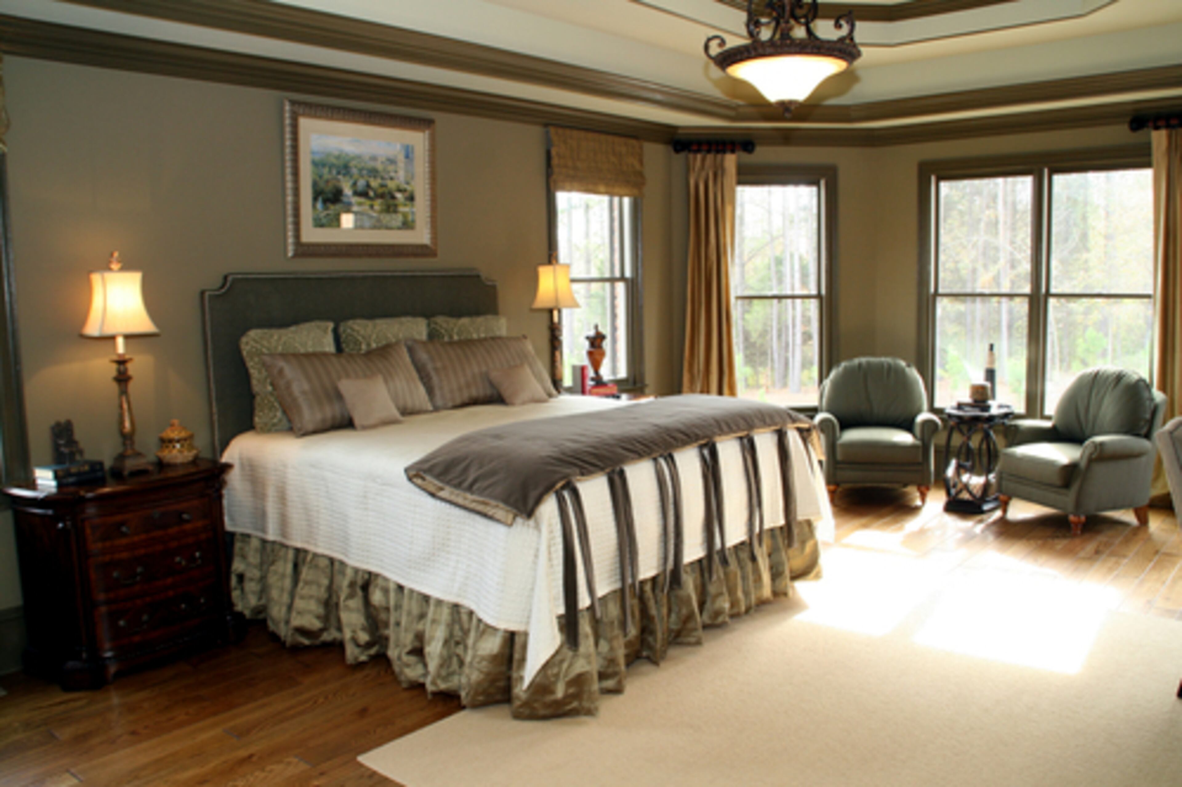 MASTER SUITE: A CherryThorne trademark is the throw with ties that decorates the bed in the master suite; tone-on-tone weaves add subtle patterns to the coverlet, pillows and bed skirt. Sage walls and comfortable chairs are accented by the dark olive trim that frames the double-tray ceiling.