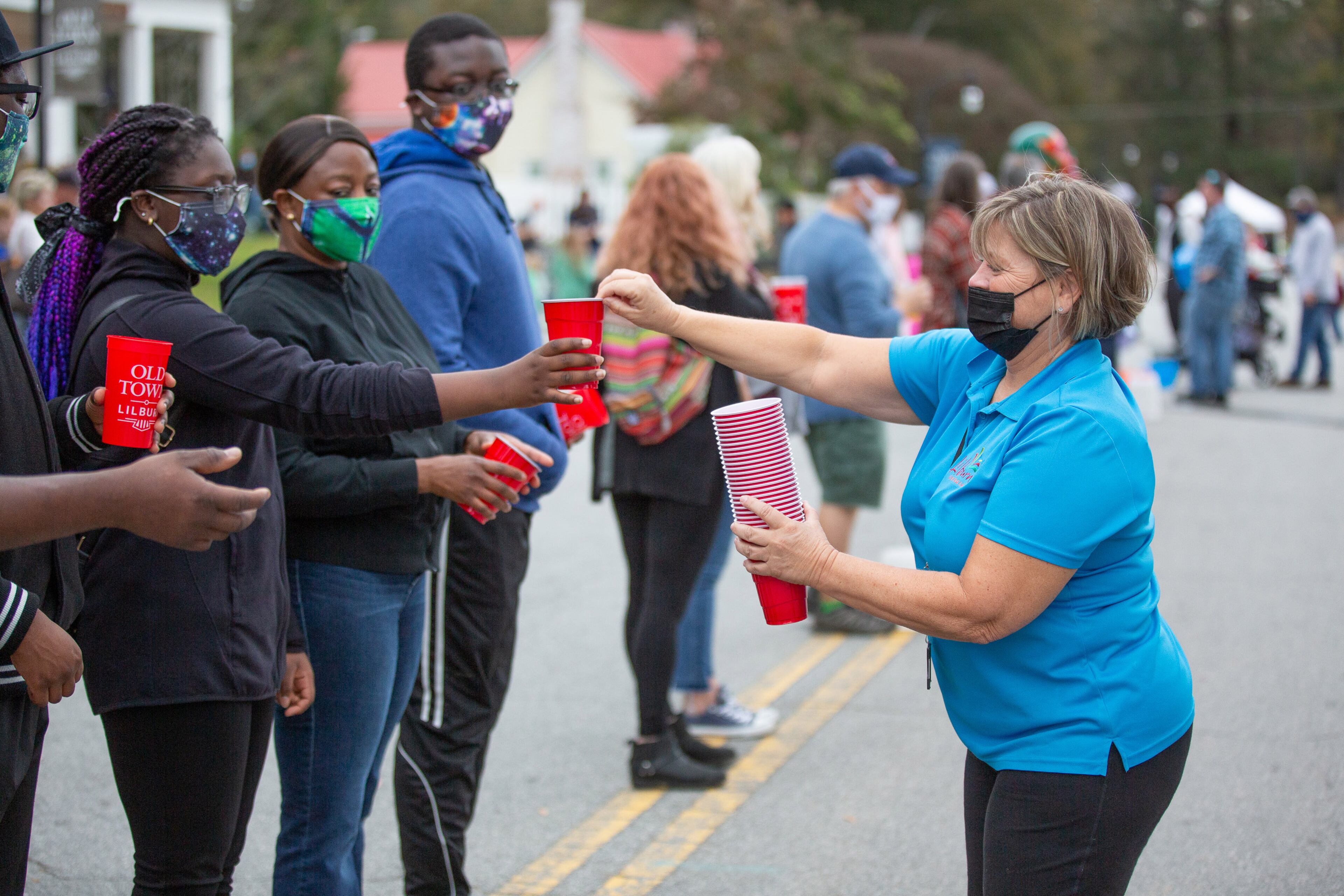Jill Williams hands out cups before the start of the bucket brigade reenactment on Sunday, November 15, 2020, to mark the 100th anniversary of when Lilburn was saved from a fire. (Photo: Steve Schaefer for The Atlanta Journal-Constitution)