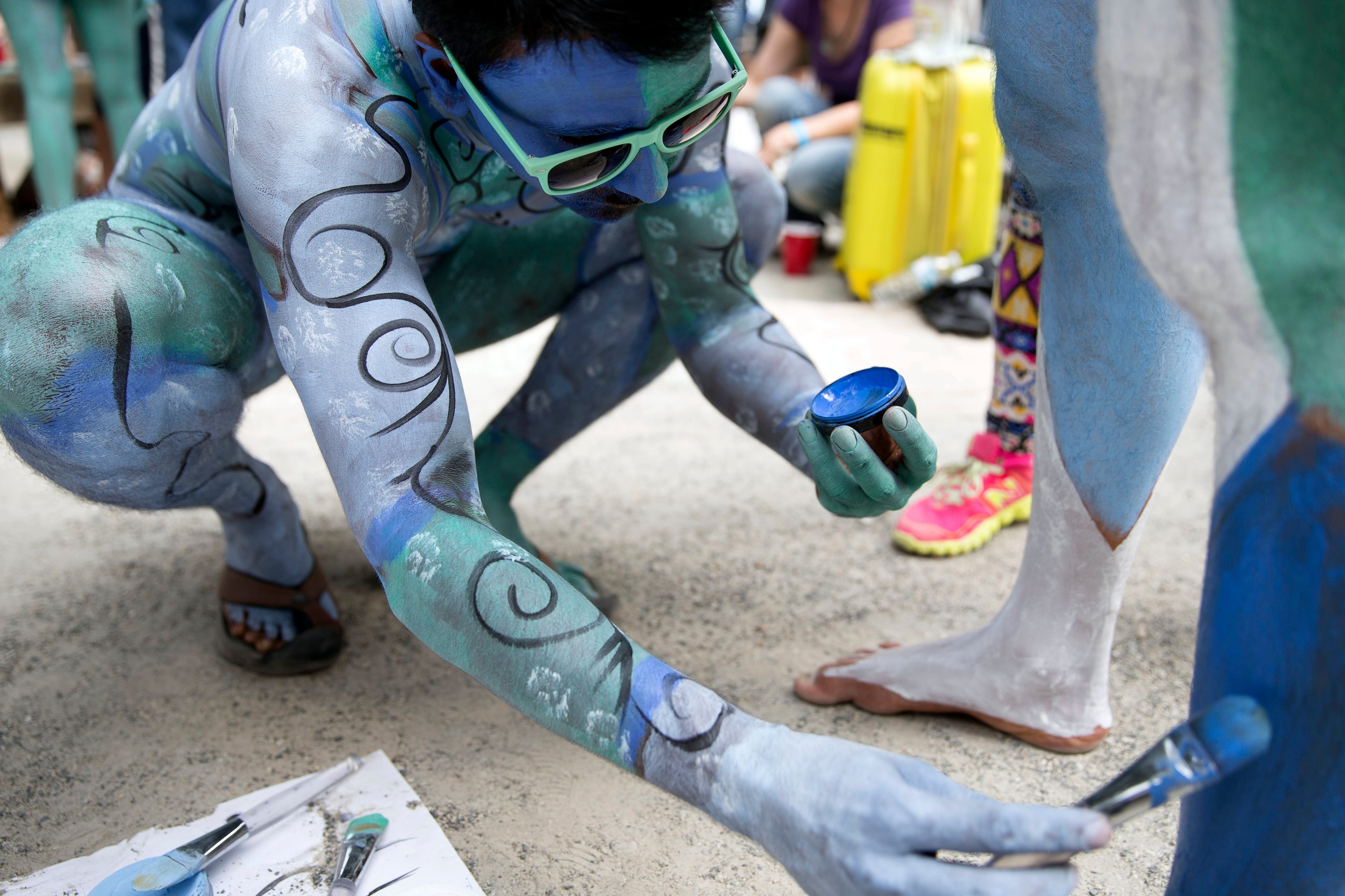 Models help paint one another at Columbus Circle as body-painting artists gathered to decorate nude models as part of an event featuring artist Andy Golub, Saturday, July 26, 2014, in New York. Golub says New York was the only city in the country that would allow his inaugural Bodypainting Day. (AP Photo/John Minchillo)