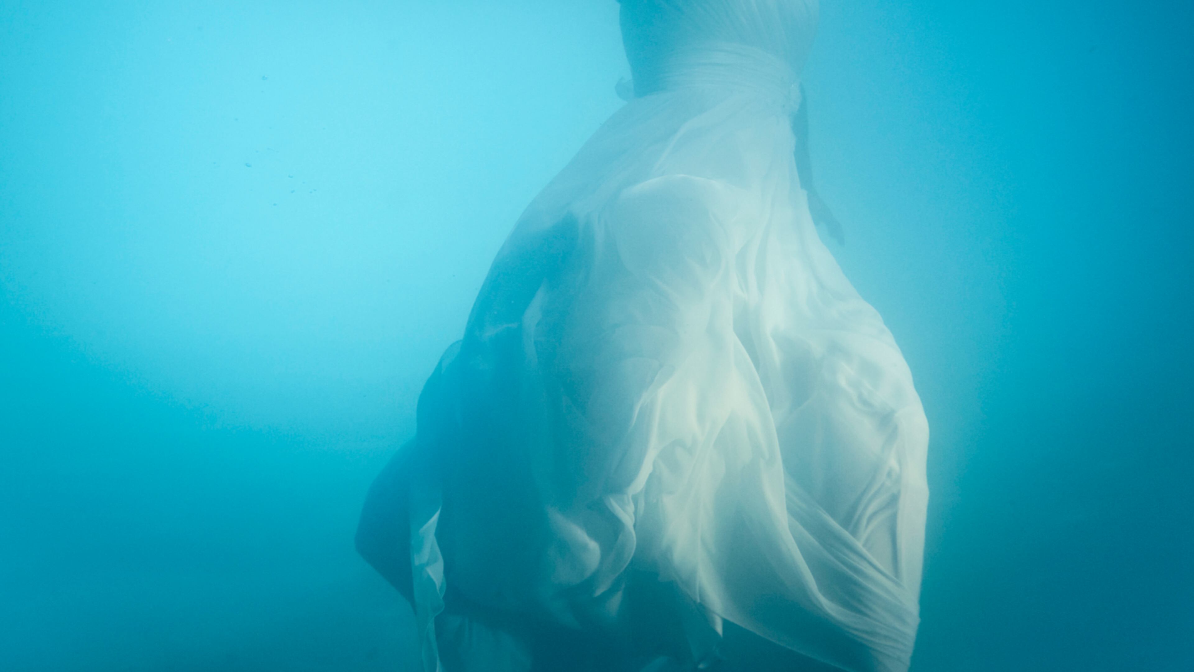 Stock image of a woman wearing a wedding dress underwater.