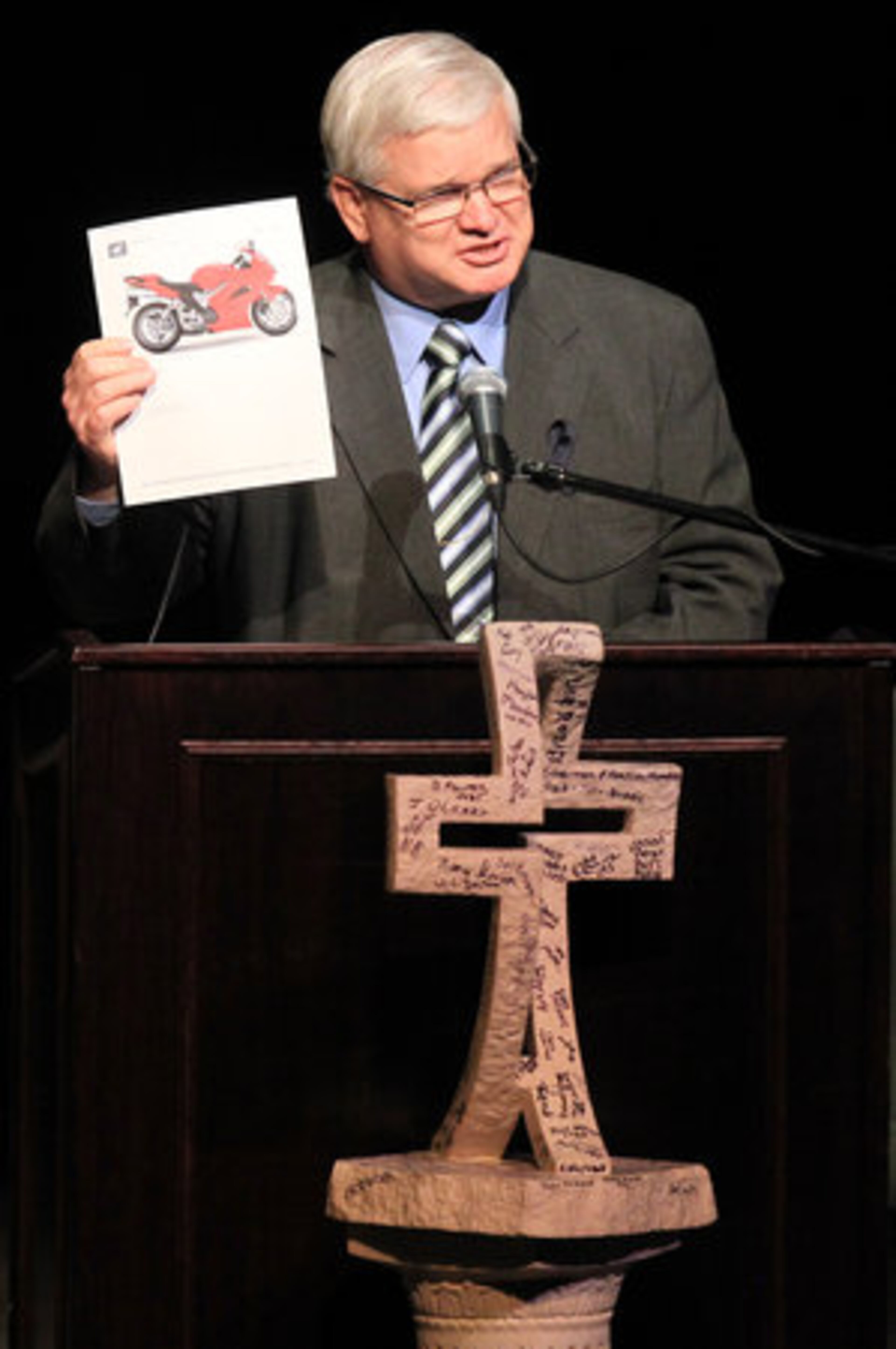 Pastor Randy Crowe pulls a picture of a motorcycle from the Bible of slain Athens Senior Police Officer Elmer "Buddy" Christian, one of his church members, while delivering the closing prayer at his memorial service in the Classic Center Theatre in Athens on Sunday, March 27, 2011.