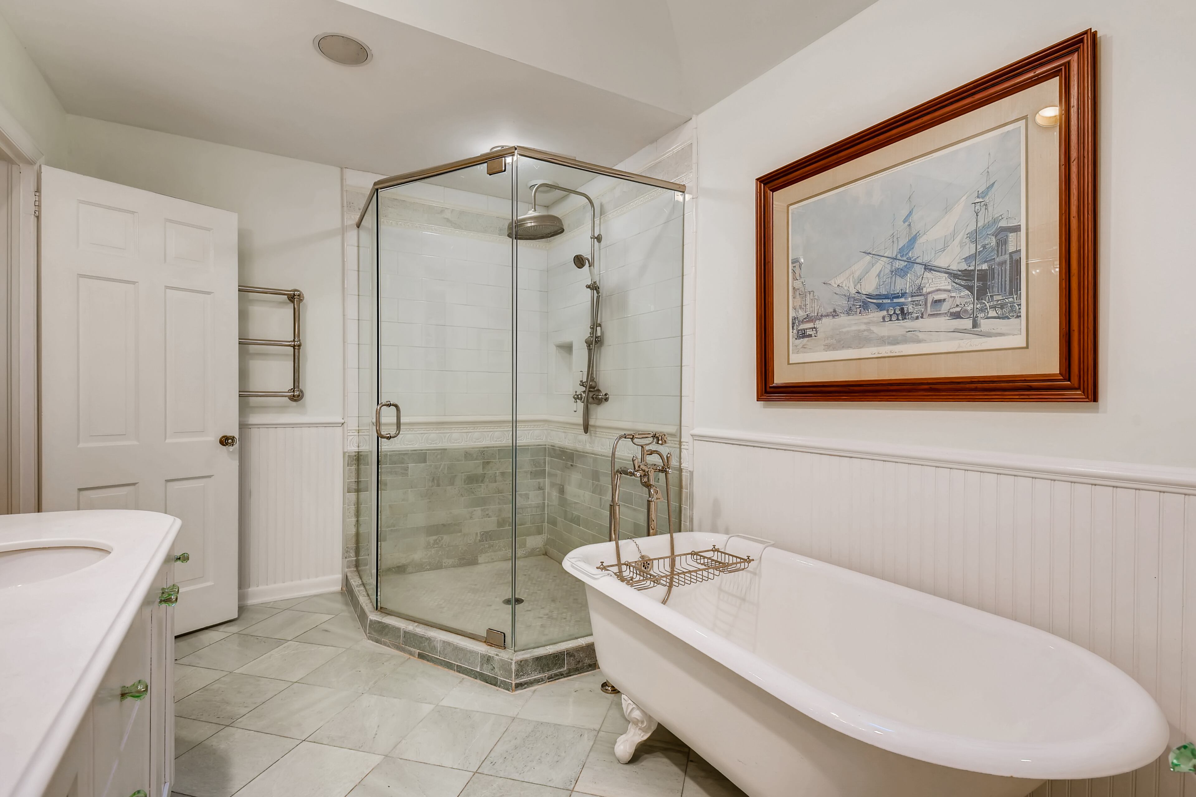 The primary bathroom features a claw foot tub, separate shower, double vanity, Waterworks fixtures, and heated marble floors. Text by Jean Bird