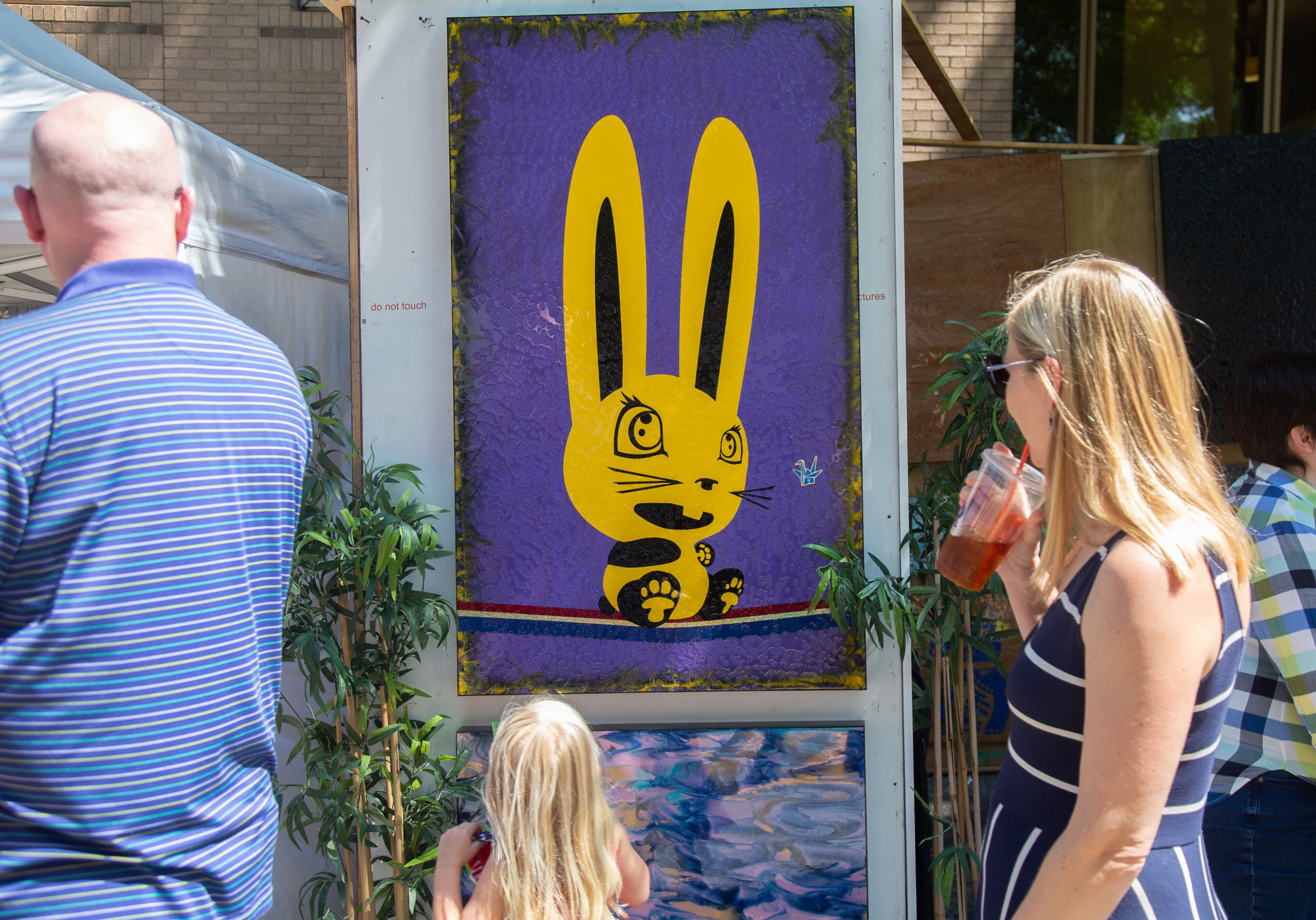 Fairgoers walk by artist John Ha's painting called Lucky Bunny during the annual Decatur Arts Festival on Sunday, May 26, 2019. STEVE SCHAEFER / SPECIAL TO THE AJC