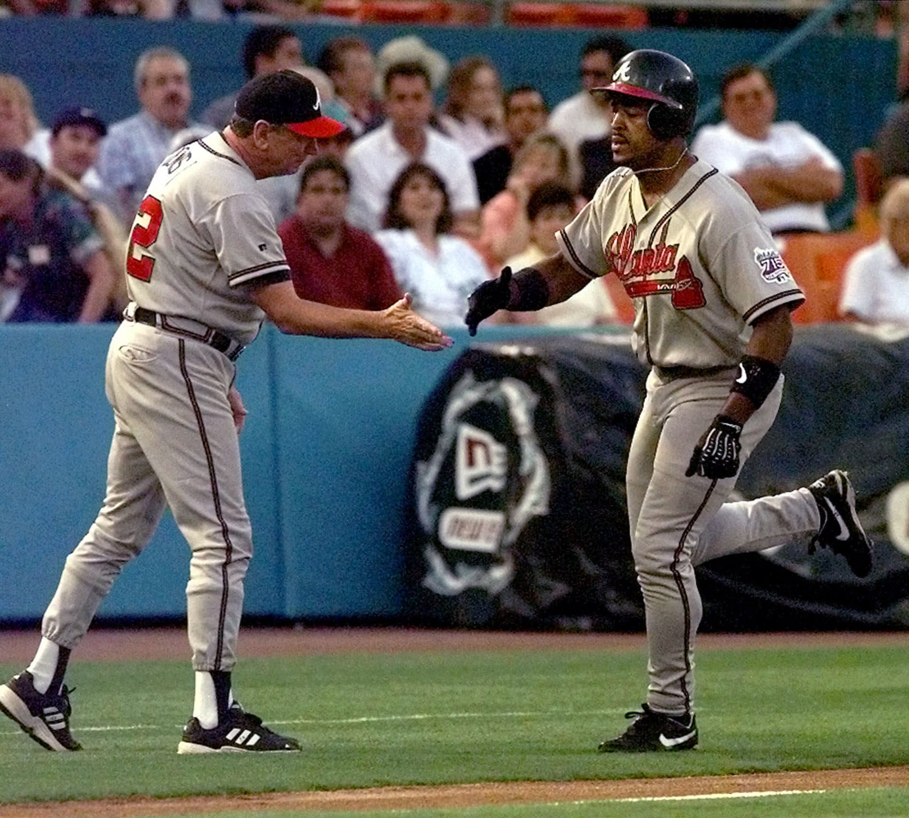 Atlanta Braves' Brian Jordan, right, receives congratulations from third base coach Bobby Dews after Jordan hit a home run in the first inning against the Florida Marlins, Saturday, April 24, 1999, at Pro Player Stadium in Miami. The home run was one of three Marlins starting pitcher Jesus Sanchez gave up in the first inning. The Braves defeated the Marlins 8-7. (AP Photo/Tony Gutierrez)