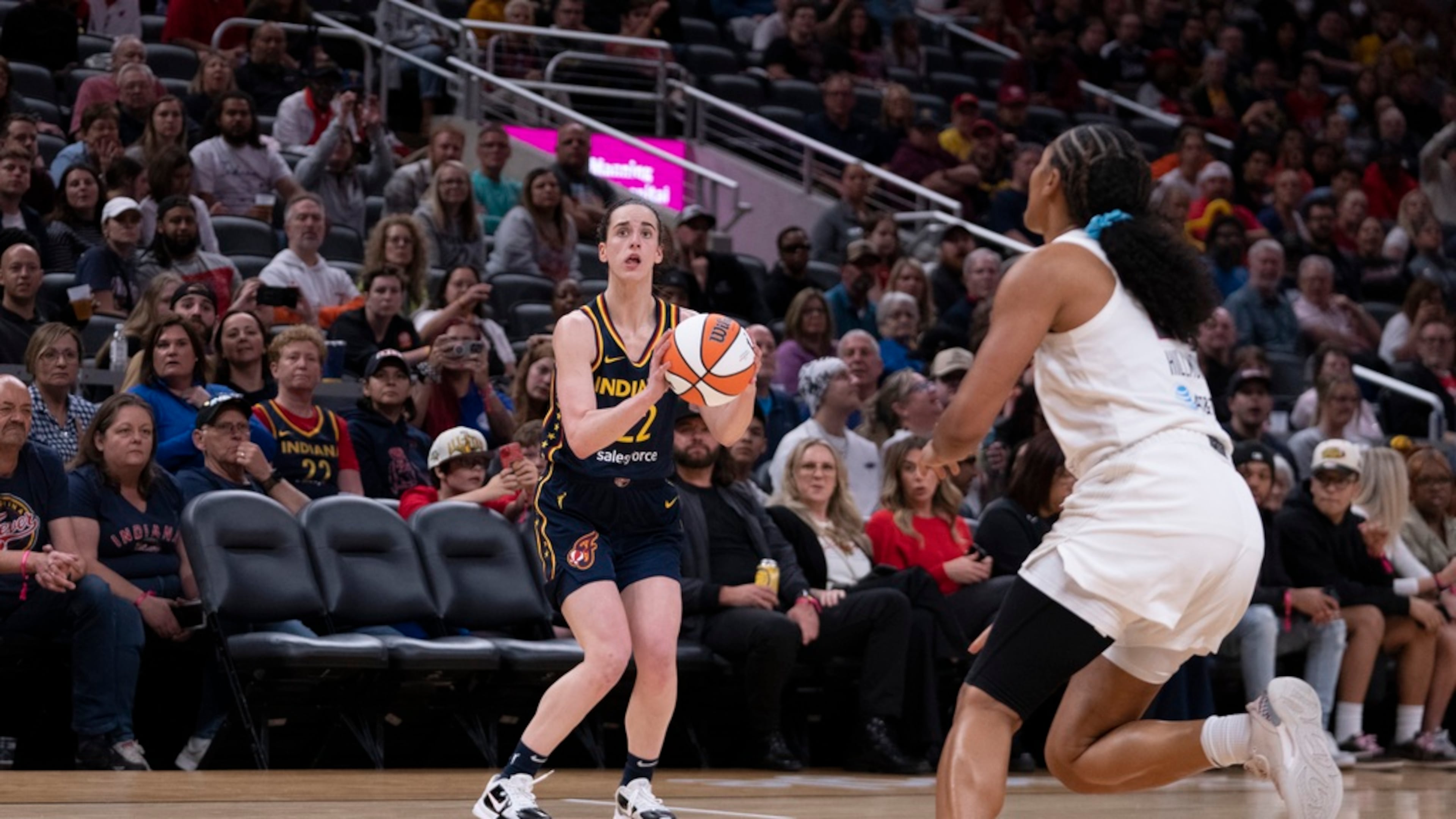Indiana Fever's Caitlin Clark (22) puts up a 3-point shot in front of Atlanta Dream's Naz Hillmon during the second half of a WNBA preseason basketball game Thursday, May 9, 2024, in Indianapolis. (AP Photo/Darron Cummings)