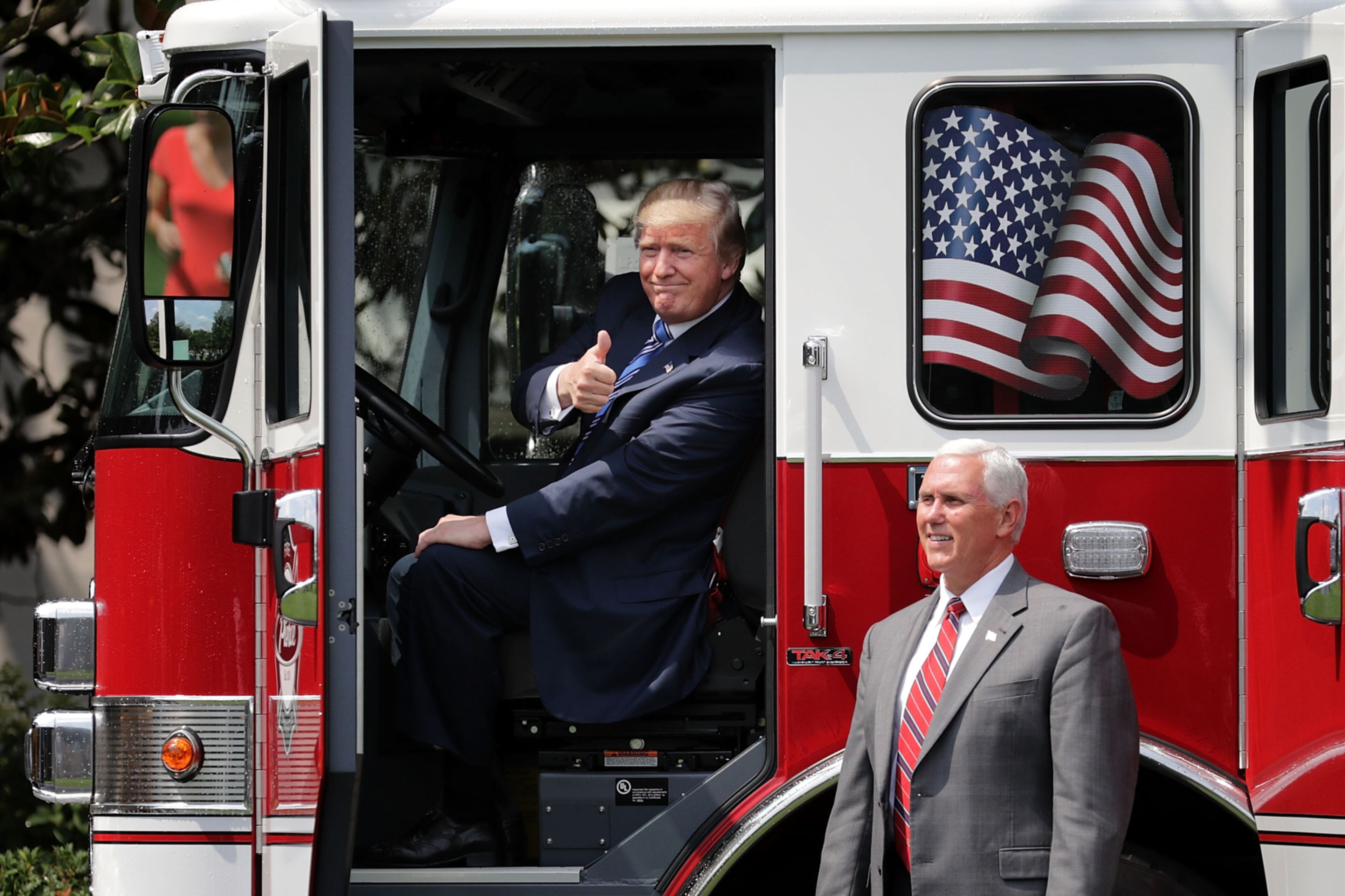 WASHINGTON, DC - JULY 17: U.S. President Donald Trump gives a thumbs up to journalists from inside a fire engine made by Pierce Manufacturing while touring a Made in America product showcase with Vice President Mike Pence on the South Lawn of the White House July 17, 2017 in Washington, DC. American manufacturers representing each of the 50 states participated in the showcase, including Bully Tools, Cheerwine, Stetson, Simms and RMA Armament, Charles Machine Works, Honckley Yachts, Altec Inc., Caterpiller, Pierce Manufacturing and others. (Photo by Chip Somodevilla/Getty Images)