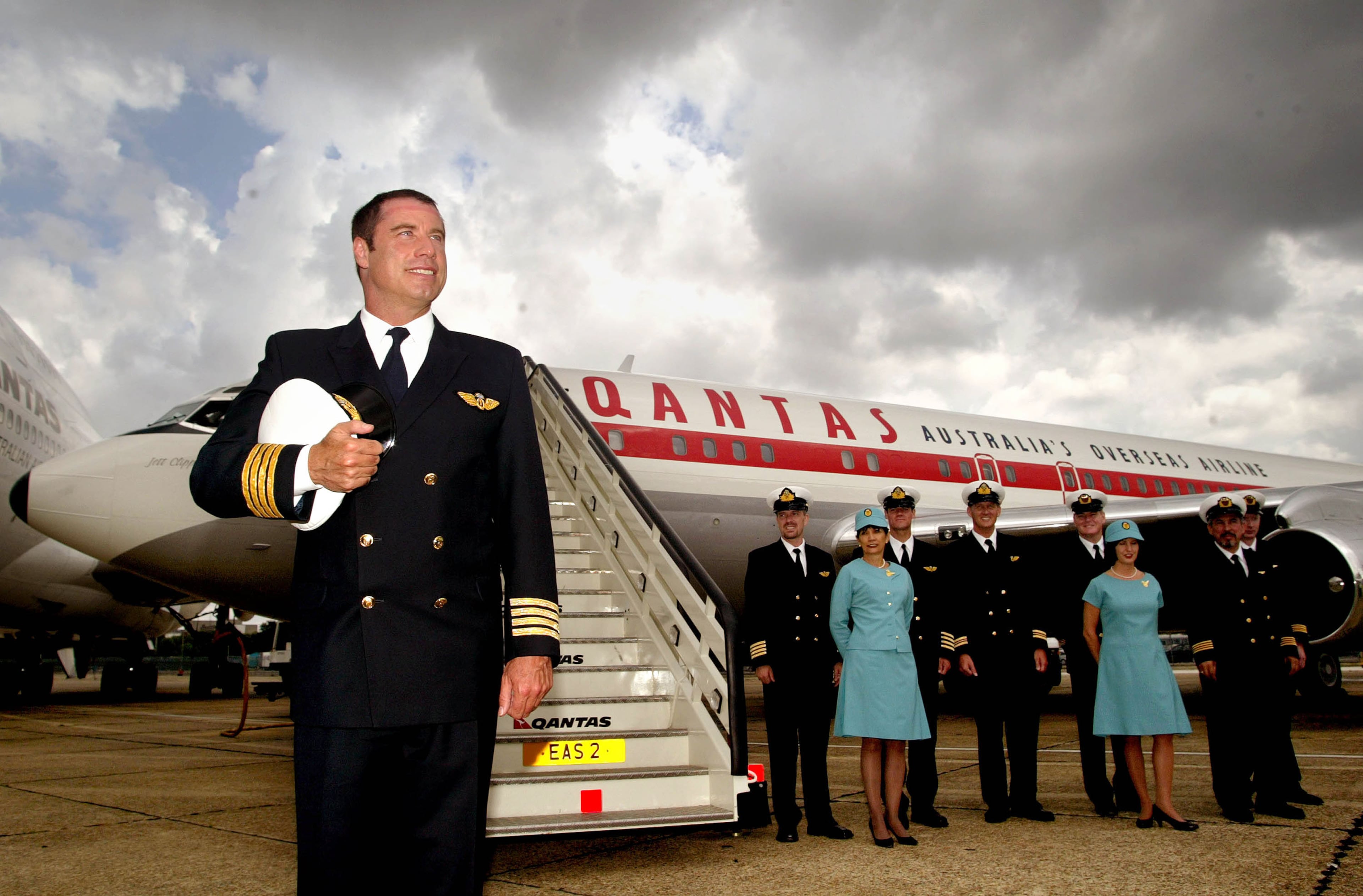 John Travolta poses with his flight crew at the staircase of his personal plane at Heathrow Airport in London in 2002. Travolta was named a brand ambassador for Australian airline Qantas and was on a 13-city "Spirit of Friendship" tour to promote and raise the post-Sept. 11 profile of air travel. (Sion Touhig/Getty Images 2002)