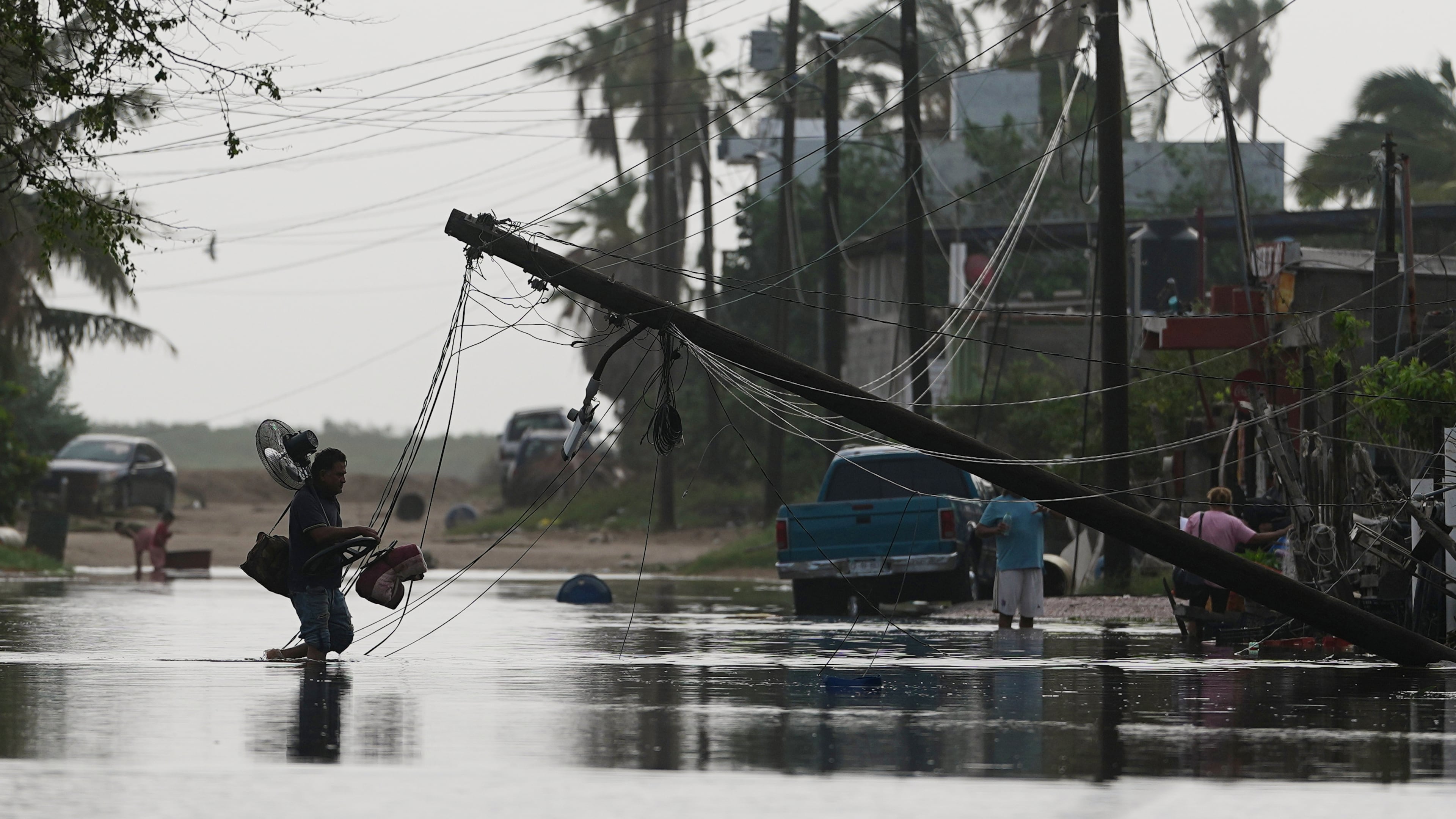 A man carries items through floodwater past downed electric lines after the passing of Hurricane Polo in Puerto San Carlos, Baja California Sur state, Mexico, Tuesday, Sept. 29, 2026. (AP Photo/Eduardo Verdugo)