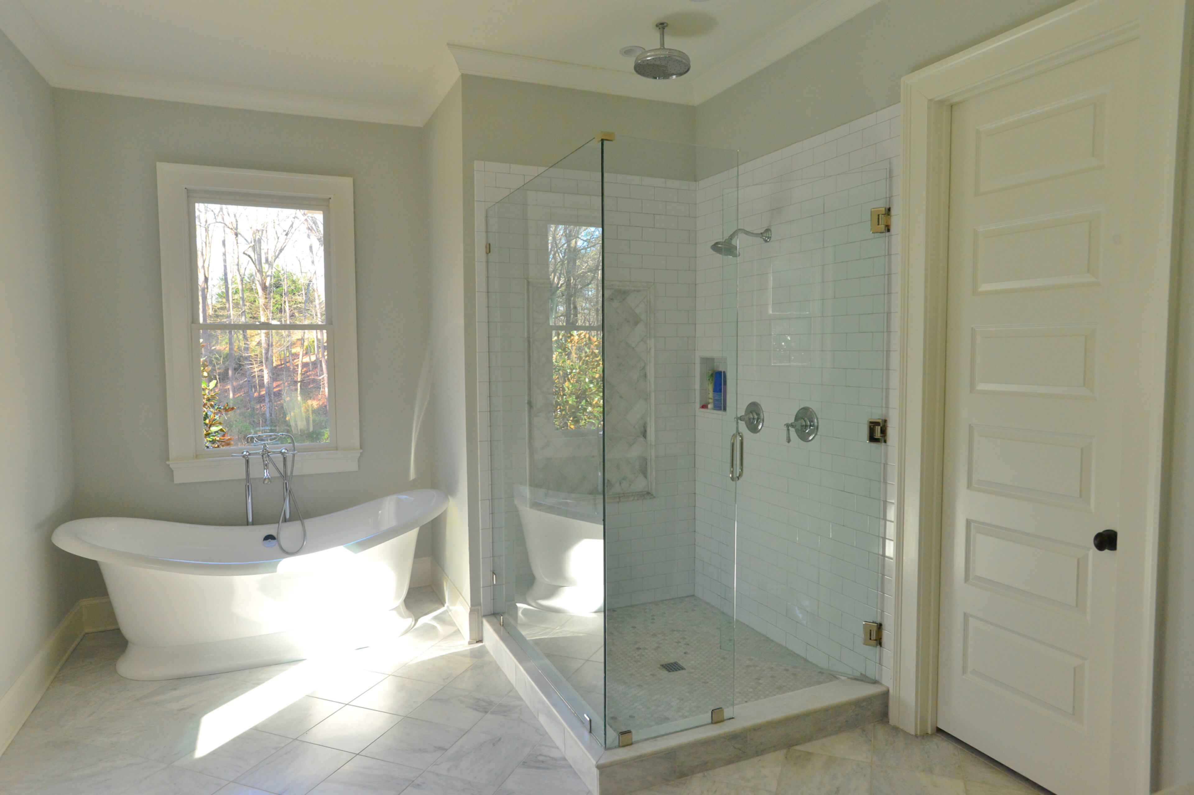 Carrera marble covers the floor in Randy and Casey Schiltz's master bath. The all-white room features a freestanding tub from Ferguson Enterprises and a large glass-enclosed shower with subway tile. Text by Lori Johnston and Keith Still/Fast Copy News Service.