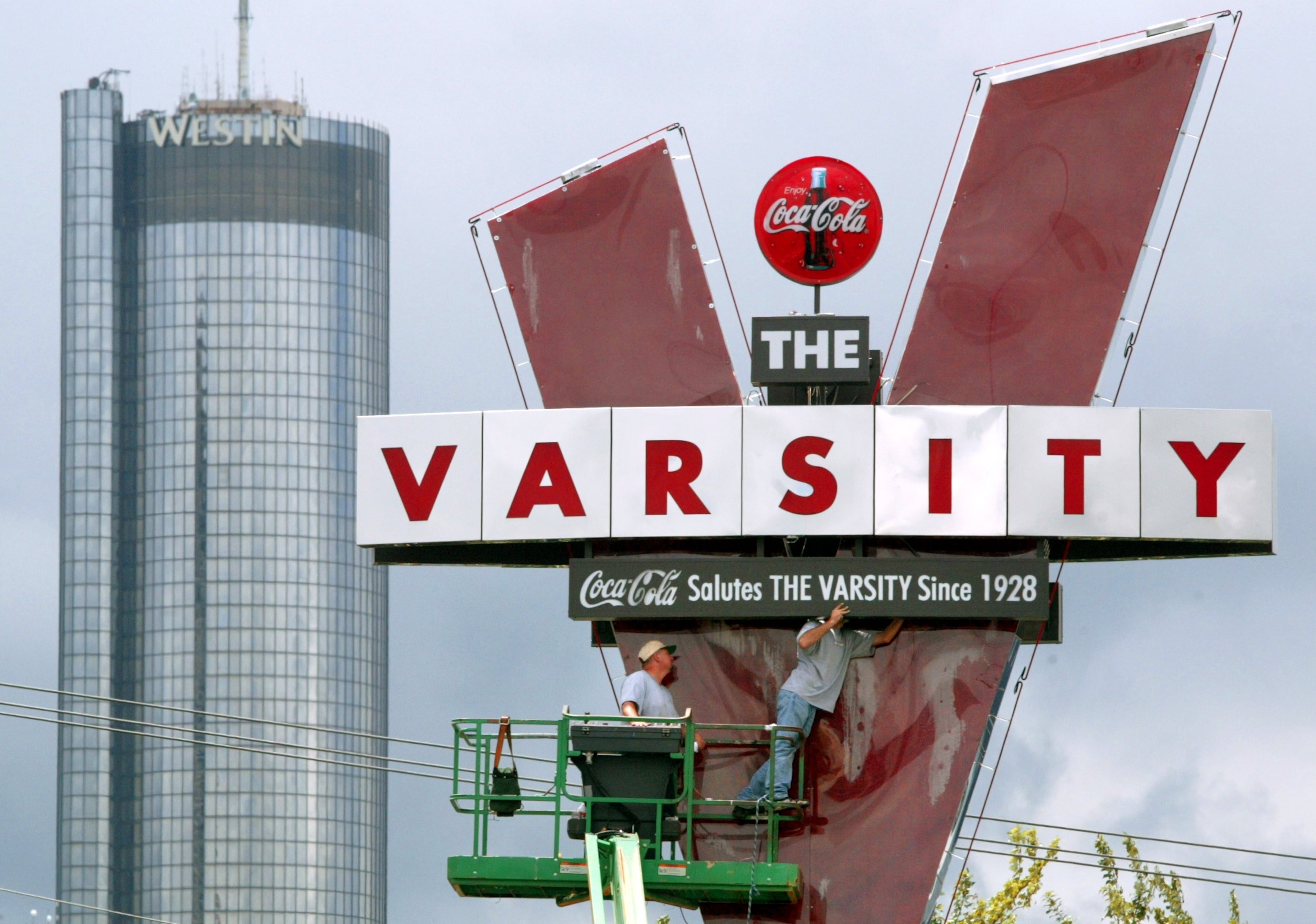 07/02/03-ATLANTA/FULTON COUNTY- Curtis McMillan (CQ)(left) and Chas Berry (CQ)(right) are heads-up in the Varsity sign as the Westin is set off in the downtown skyline. The pair who work for J and J Contracting Co. have refaced both sides of the sign, repainted and rebuilt the landmark and now wait for some fiber optics to be delivered and installed before they call it a job. The Varsity restaurant are celebrating their 75th anniversary this year.(PHOTO BY JOHN SPINK)