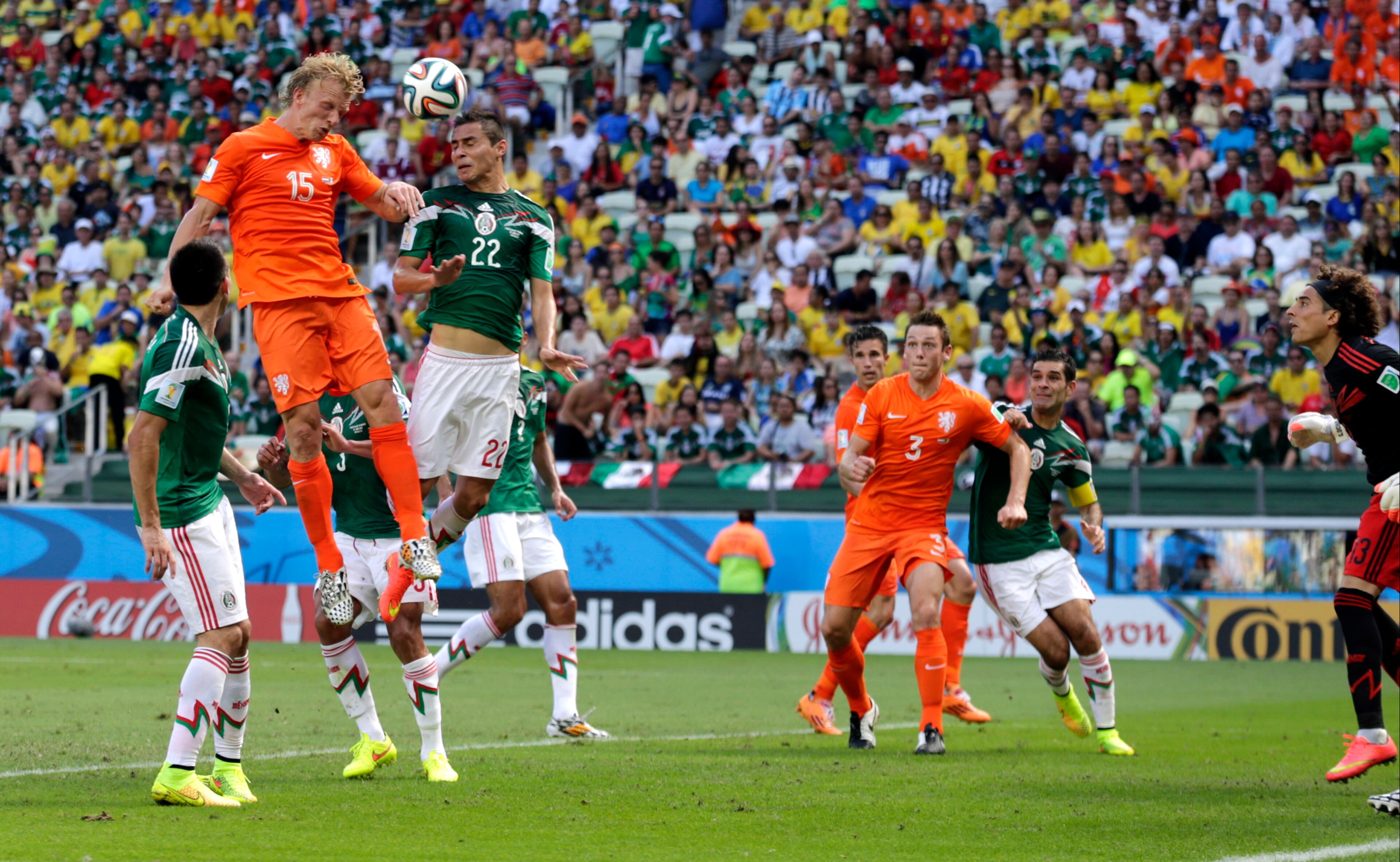Netherlands' Dirk Kuyt, left, has a header at goal against Mexico's Paul Aguilar (22) during the World Cup round of 16 soccer match between the Netherlands and Mexico at the Arena Castelao in Fortaleza, Brazil, Sunday, June 29, 2014. (AP Photo/Wong Maye-E)