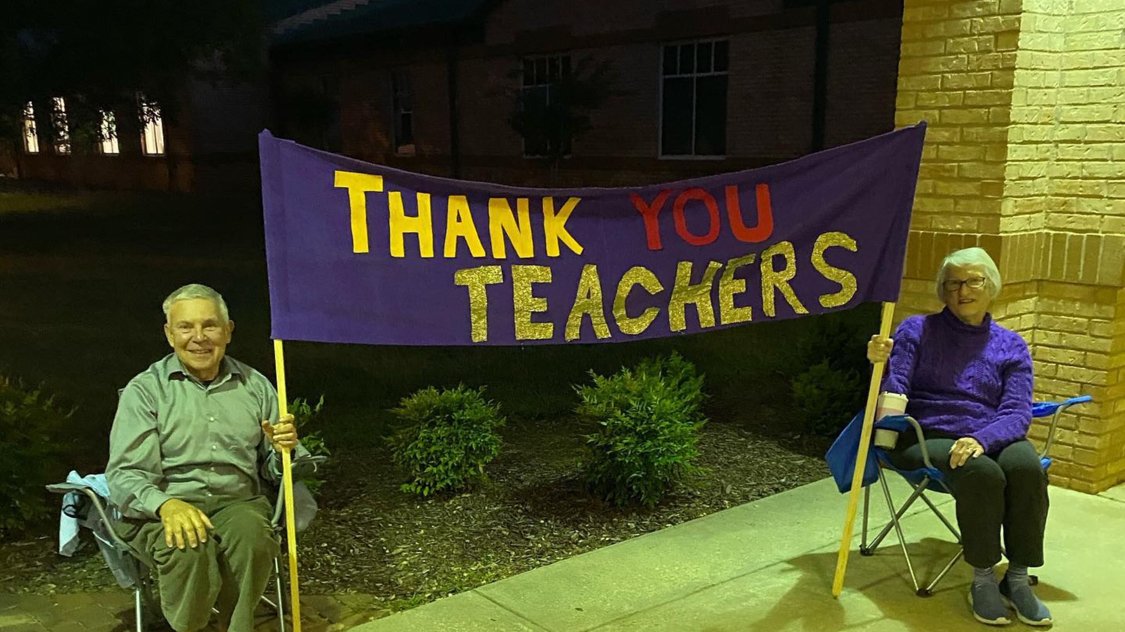 Barry and Carol Walton sat outside Kedron Elementary School in Peachtree City one morning in November 2020 with this handmade sign to thank teachers for their work. The couple were grandparents to students at the school. (Courtesy photo)