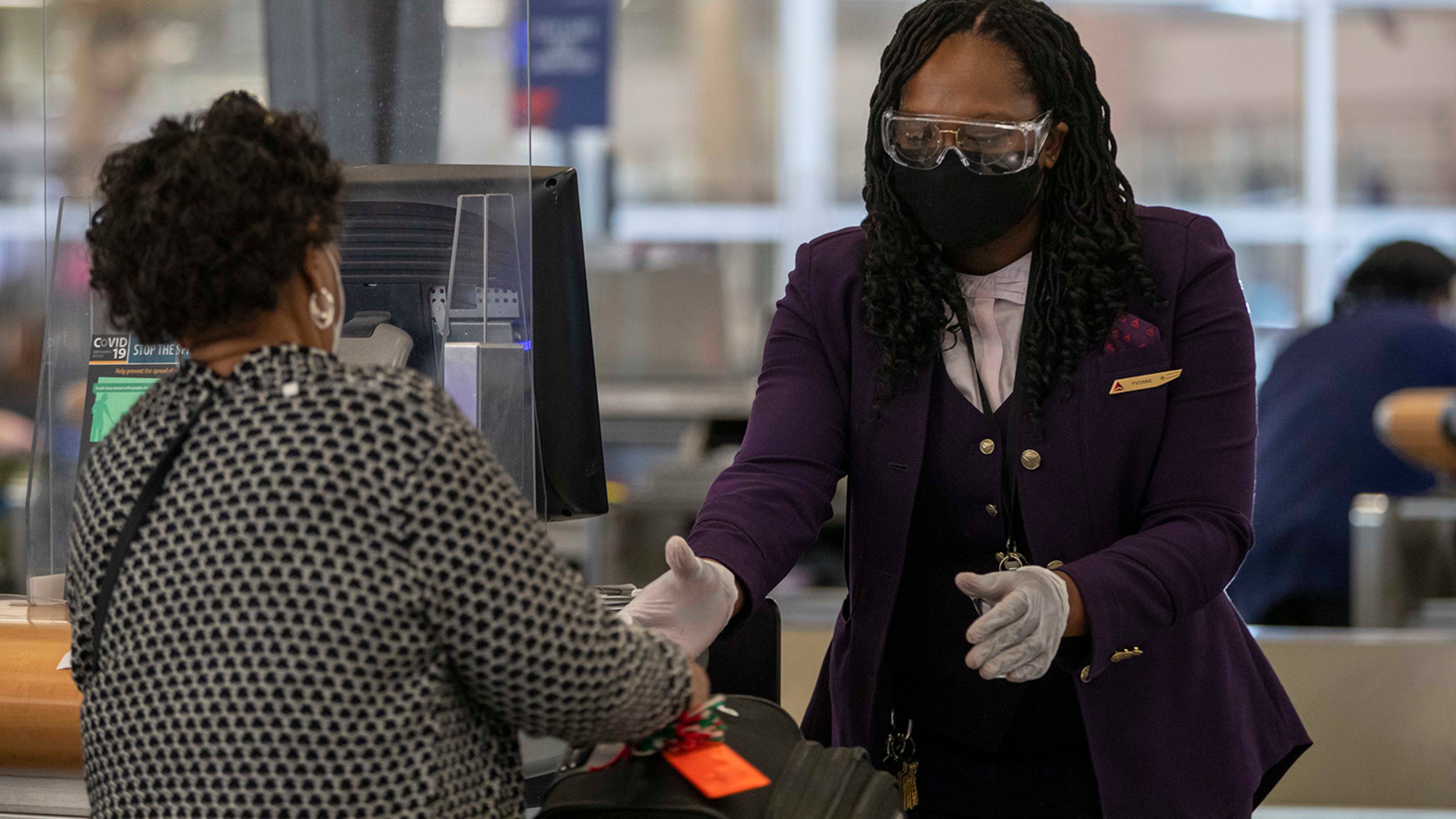 A Delta Air Lines employee handles a passenger's luggage while wearing goggle, gloves and a face mask in the domestic terminal at Hartsfield-Jackson Atlanta International Airport in Atlanta on Monday, Nov. 23, 2020. (Alyssa Pointer/Atlanta Journal-Constitution/TNS)