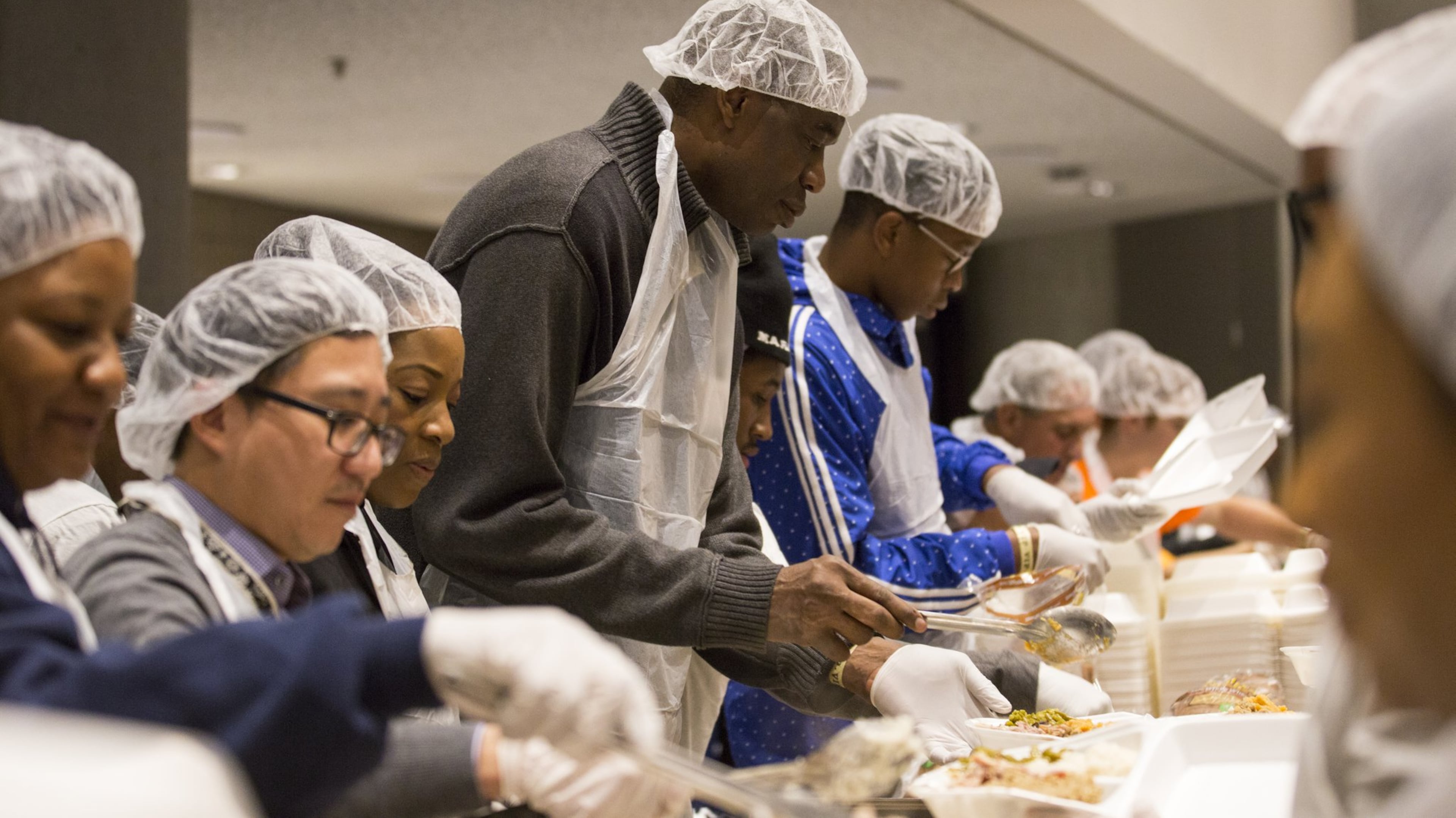 Former Atlanta Hawks player Dikembe Mutombo, center, serves meals during the annual Hosea Helps Thanksgiving dinner at the Georgia World Congress Center in 2017. ALYSSA POINTER/ALYSSA.POINTER@AJC.COM