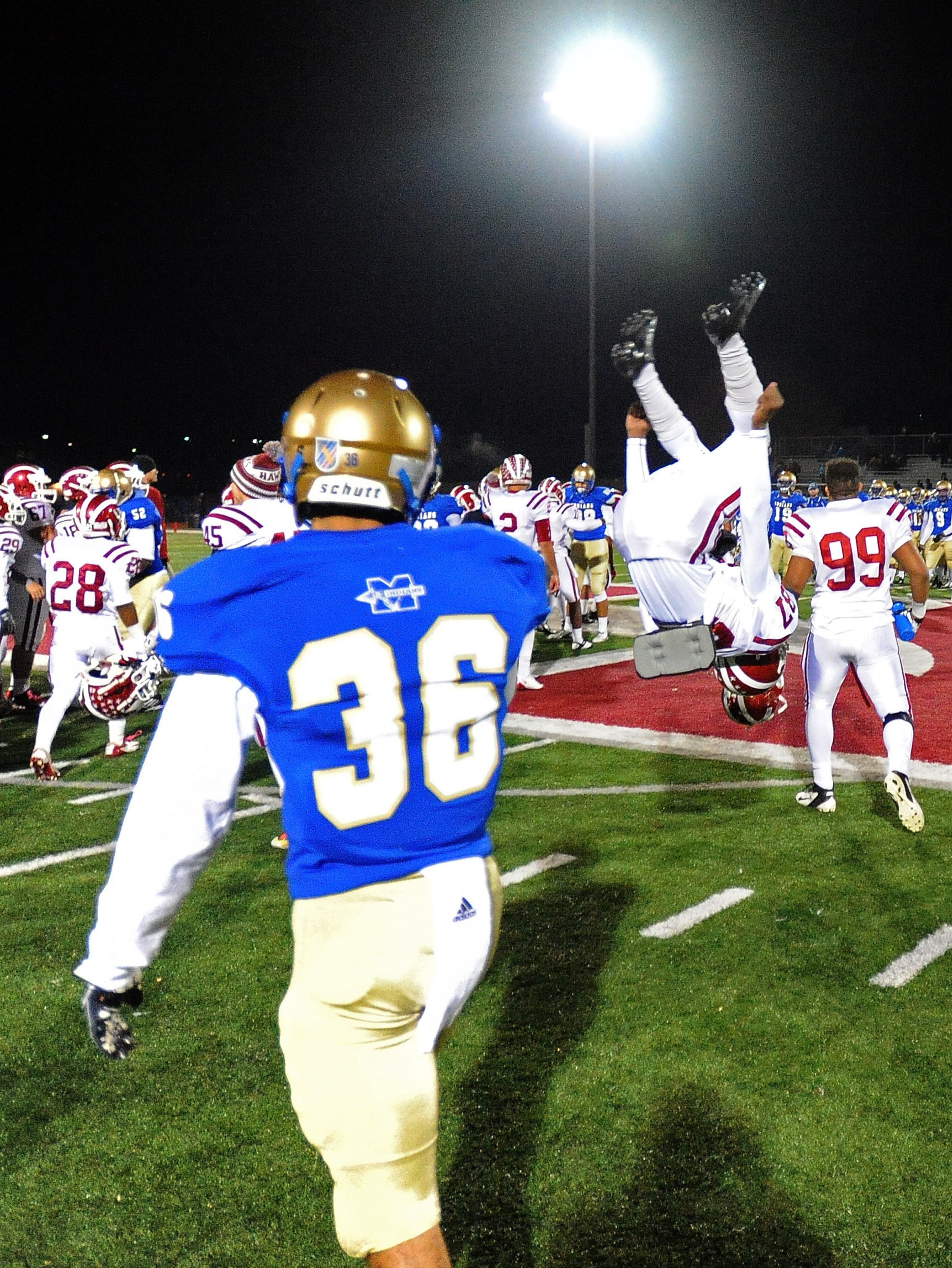 McEachern's Corey Batts (36) walks by as Hillgrove's DeAndre Beal does a midfield celebratory flip after their 31-17 win over McEachern on Friday, Nov. 8, 2013, in Powder Springs, Ga.