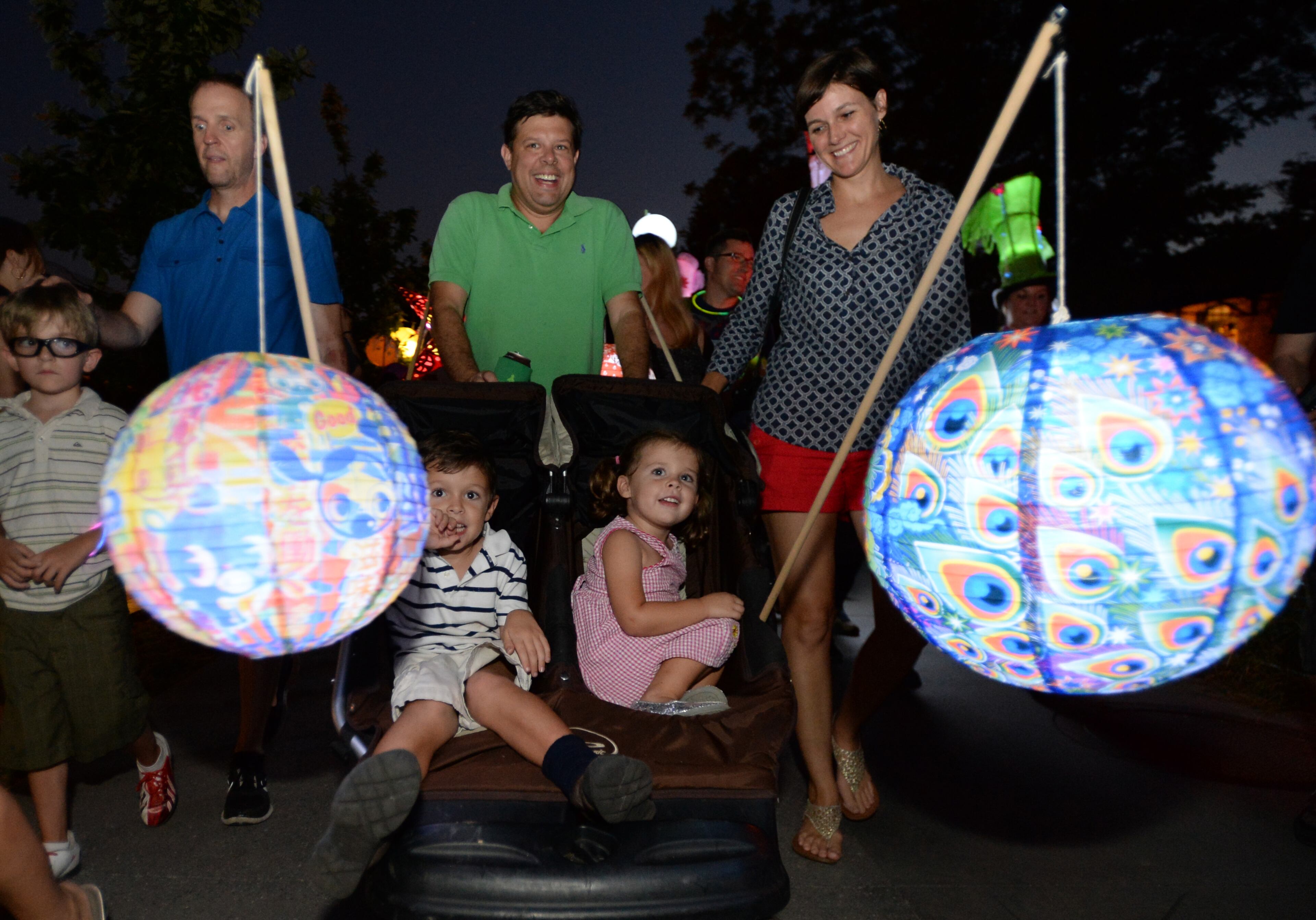 Mark (center) and Katy Stedina (right) push their children Adam (center, left), 6, and Sara, 3, during the 2013 Atlanta BeltLine Lantern Parade on Sept. 7, 2013.