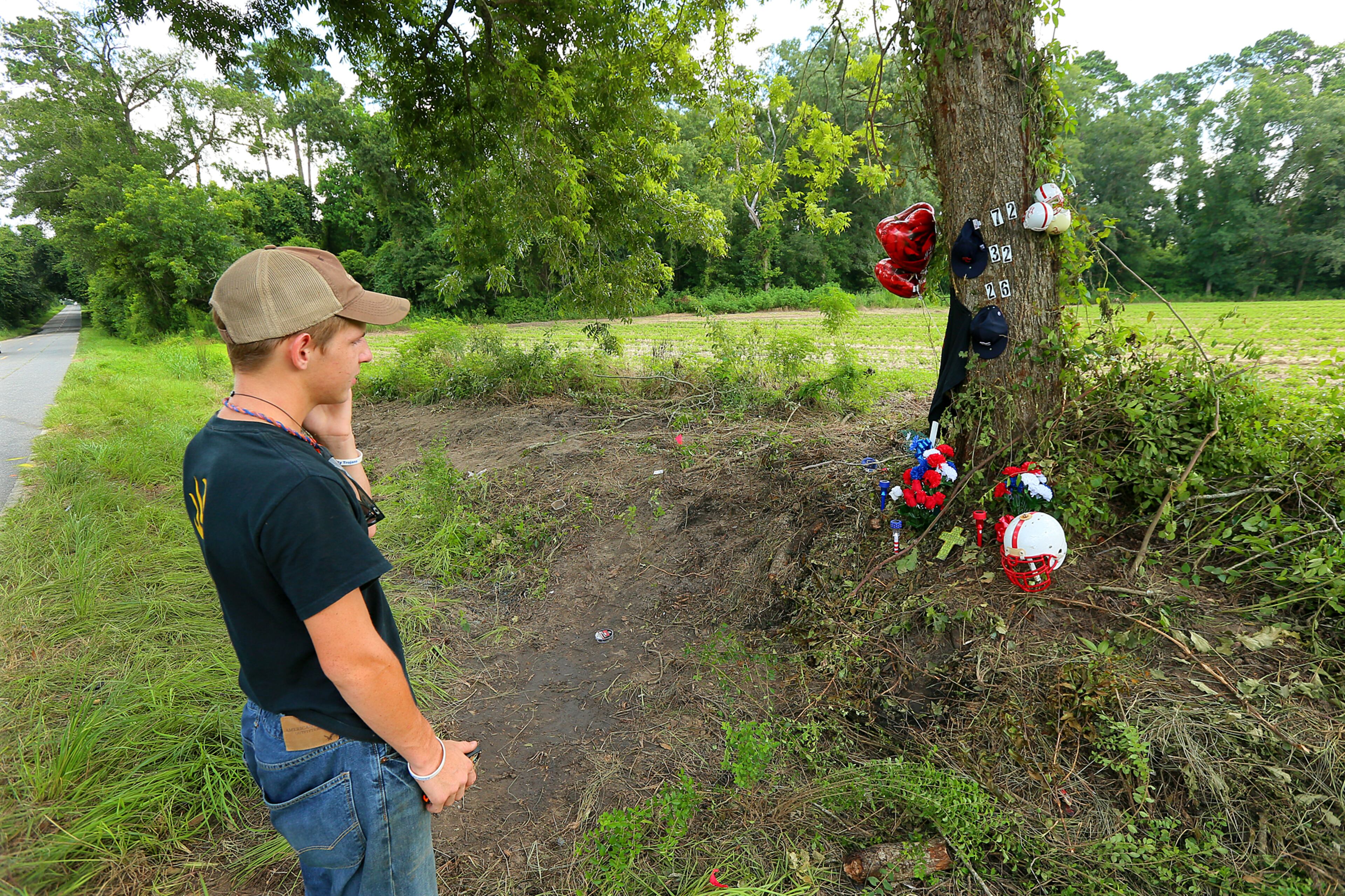 Brooks County High School student Culton Hayes, 17, looks over the shrine at the crash site that killed three of the school's football players on Wednesday, July 10, 2013, in Quitman.