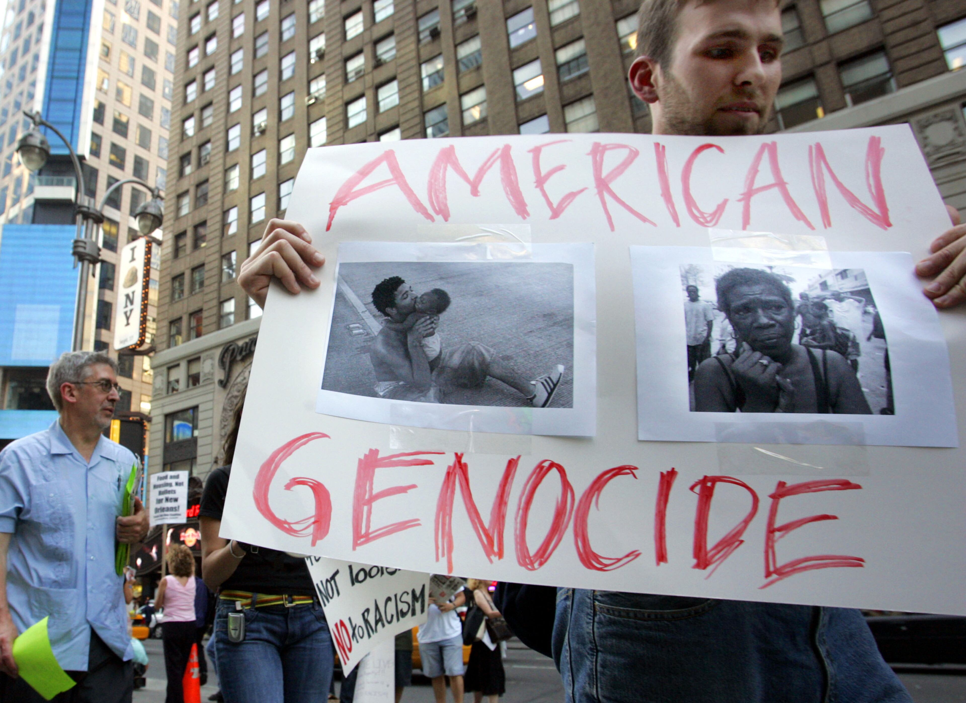 A demonstrator carries a sign with pictures of victims of Hurricane Katrina in front of the armed forces recruiting center September 2, 2005 in Times Square in New York City. About 100 people gathered to call for money to be re-directed from the war in Iraq to Katrina victims. (Photo by Stephen Chernin/Getty Images)