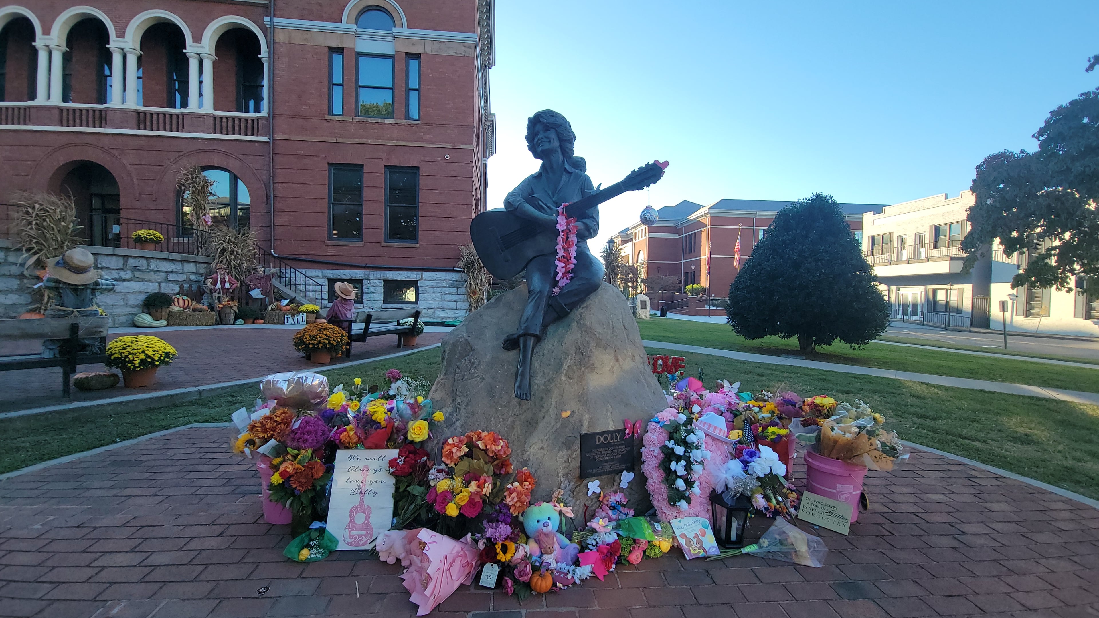 Flowers surround the statue of Dolly Parton in her hometown of Sevierville, Tennessee, where visitors leave tributes to the country music icon. (Tracey Teo for the AJC)