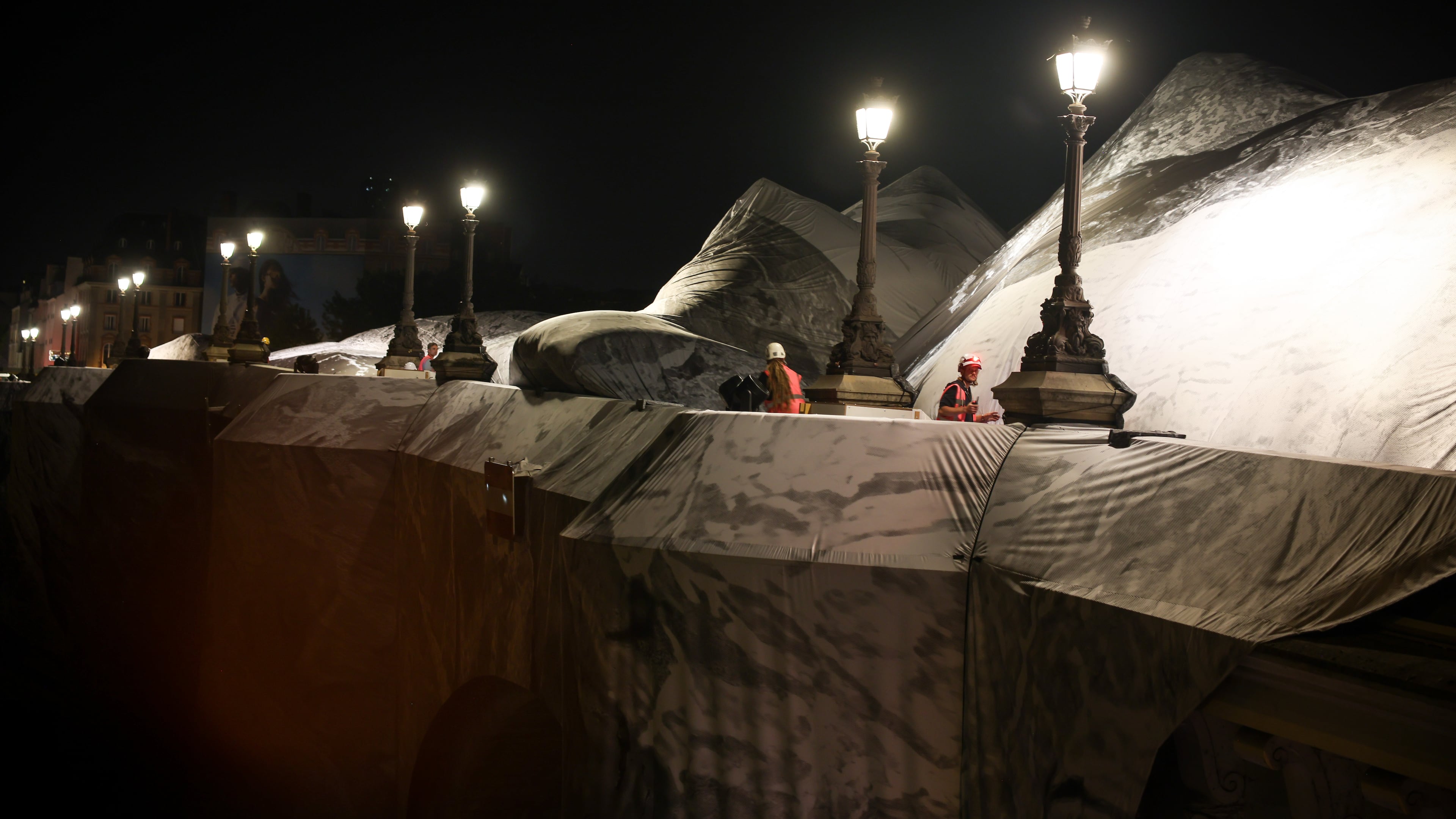A worker monitors the inflation of "The Pont Neuf Cave" by French street artist JR on the Pont Neuf bridge in Paris on Wednesday, May 20, 2026, before its free public opening from June 6 to 28. (AP Photo/Thomas Padilla)