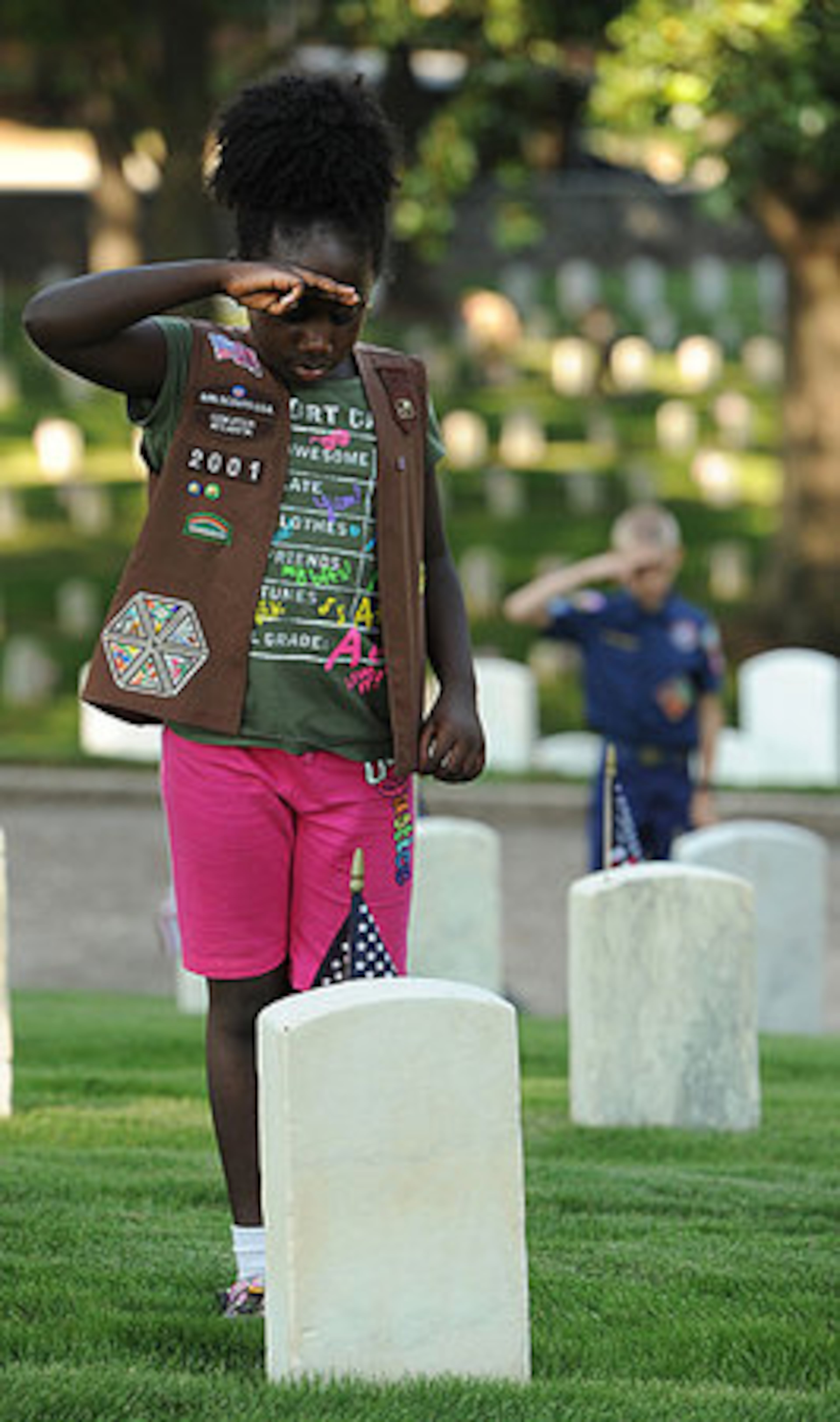 Caleigh Johnson, Brownie from Troop 2001, 8, salutes a grave after placing a flag on the headstone at the Marietta National Cemetery , on Saturday, May 26, 2012. Over 1800 Boys Scouts, Girl Scouts, Cub Scouts and Brownies placed flags on graves.