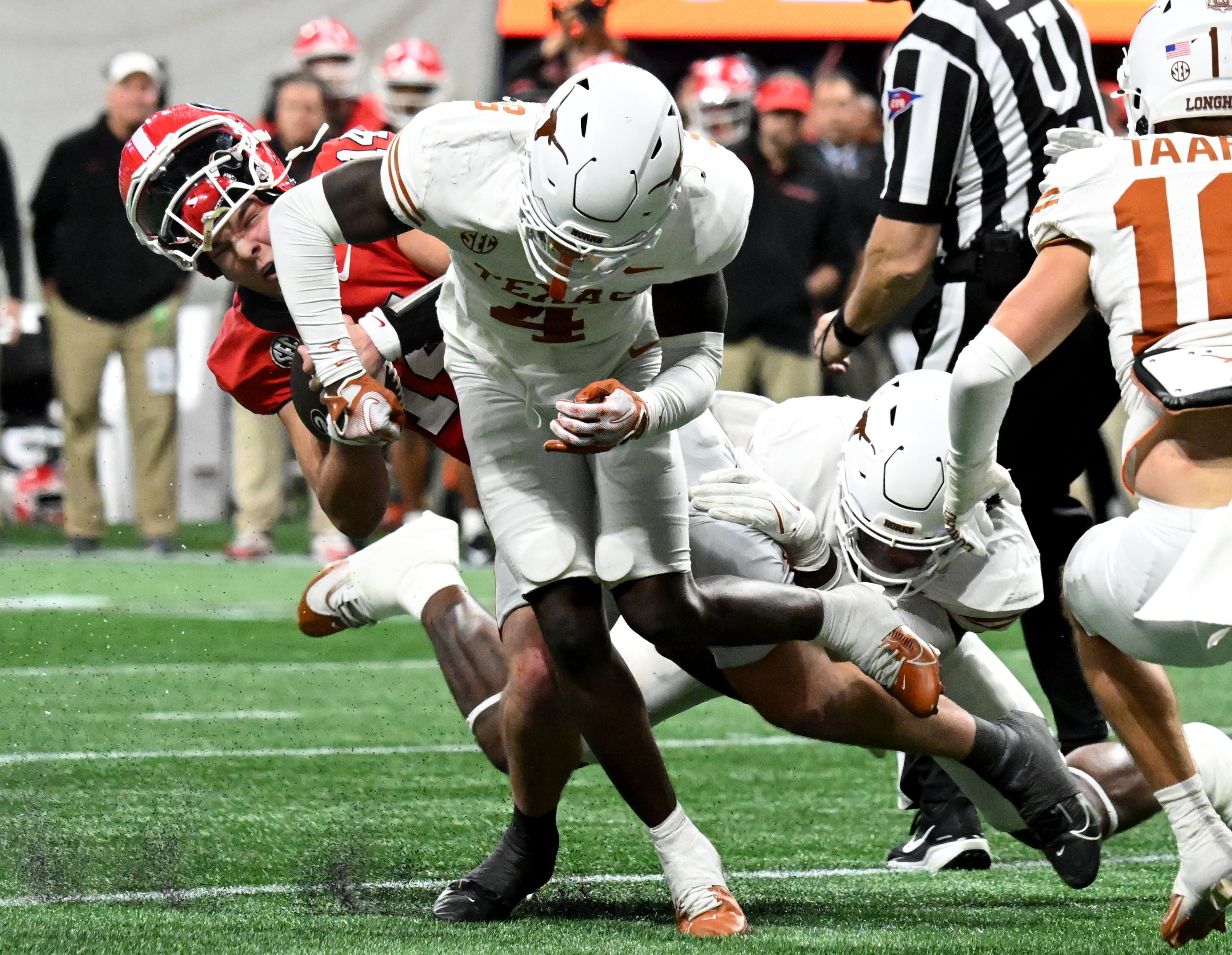 Georgia quarterback Gunner Stockton (14) gets hit by Texas defensive back Andrew Mukuba (4) in overtime during the SEC Championship football game at the Mercedes-Benz Stadium, Saturday, December 7, 2024, in Atlanta. Georgia won 22-19 over Texas in overtime. (Hyosub Shin / AJC)