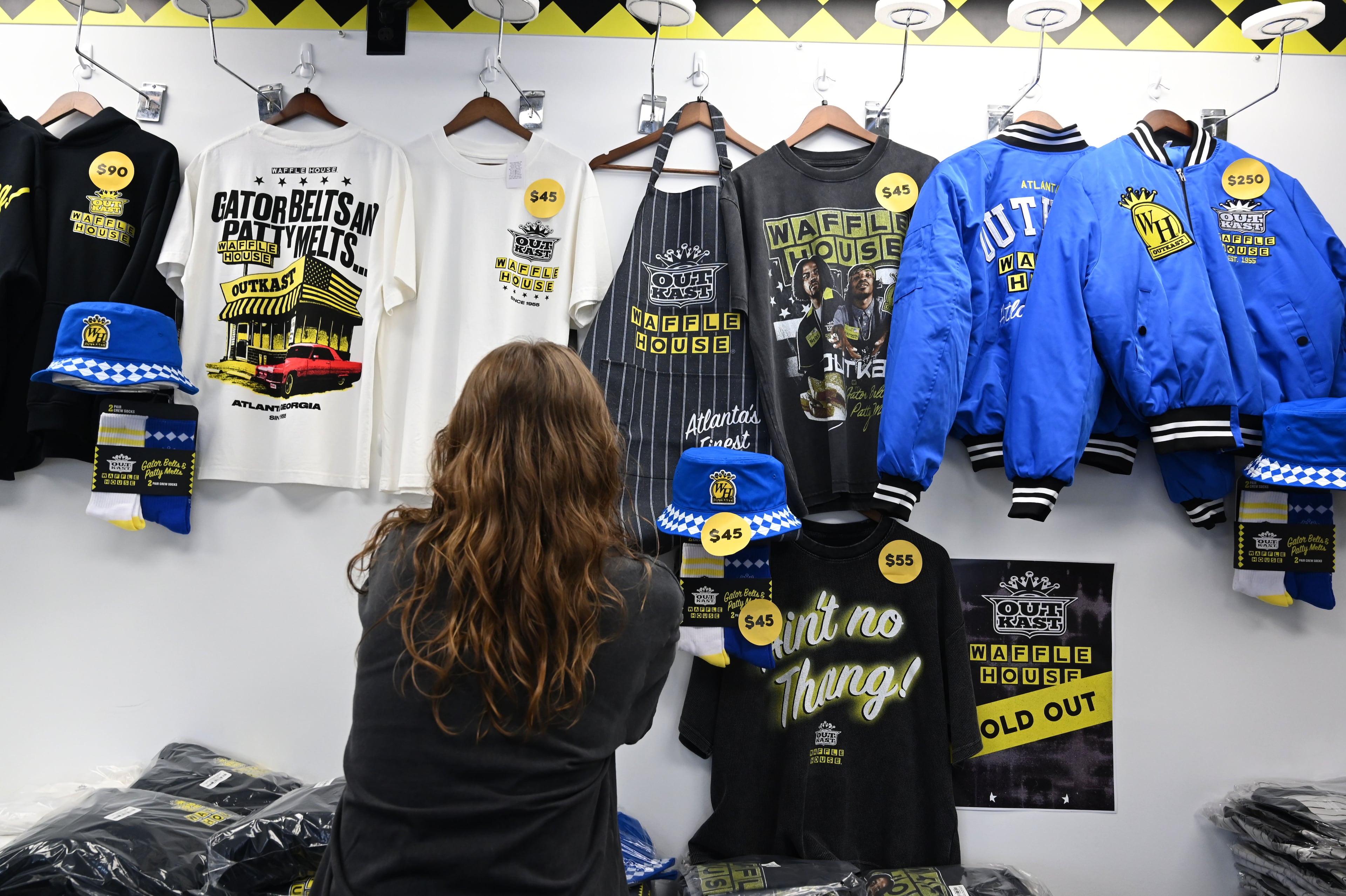 Event staff display limited-edition apparel and accessories from the Outkast and Waffle House collaboration. (Hyosub Shin/AJC)