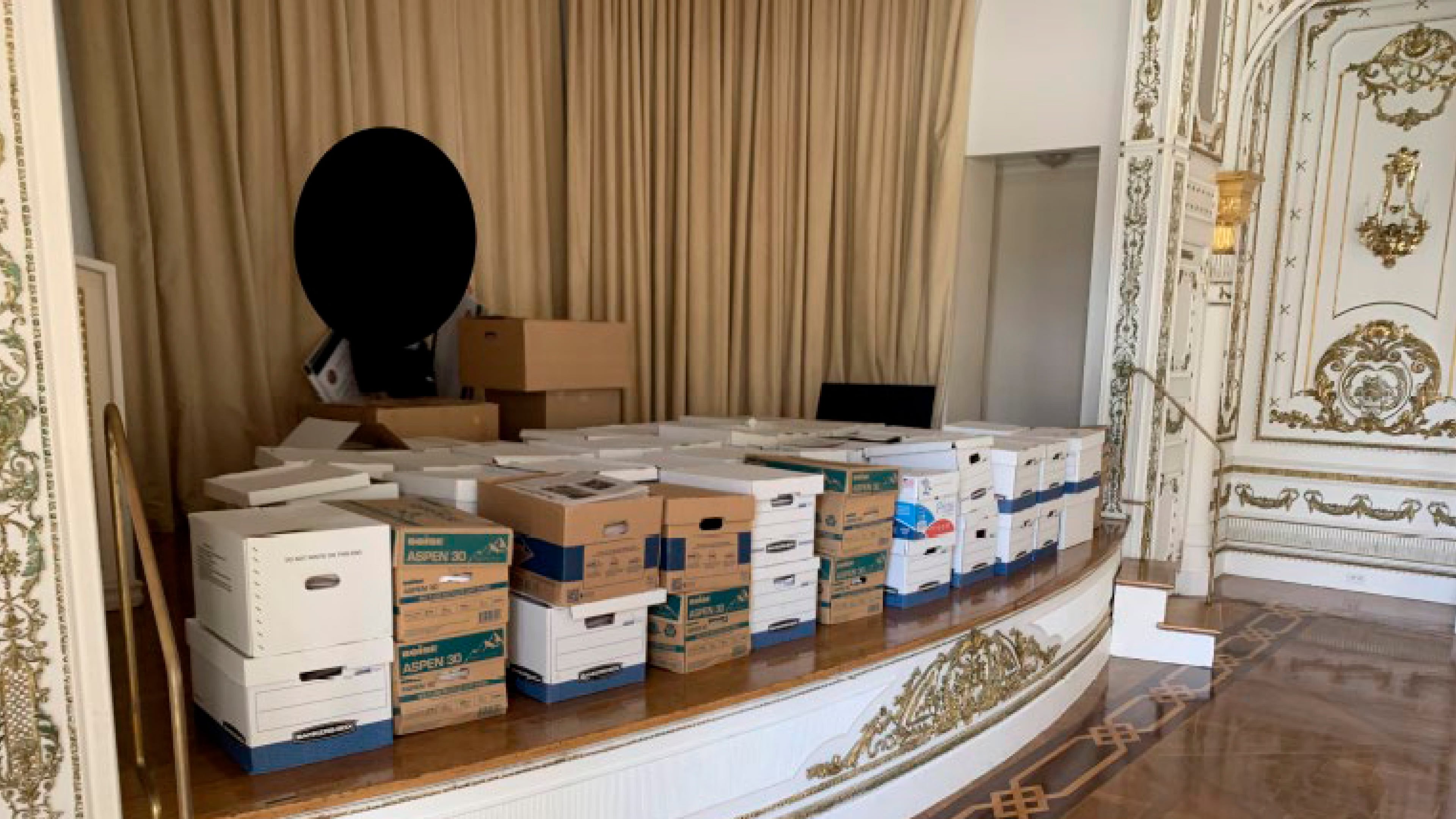 This image, contained in the indictment against former President Donald Trump, and partially redacted by source, shows boxes of records being stored on the stage in the White and Gold Ballroom at Trump's Mar-a-Lago estate in Palm Beach, Fla. (Justice Department via AP)