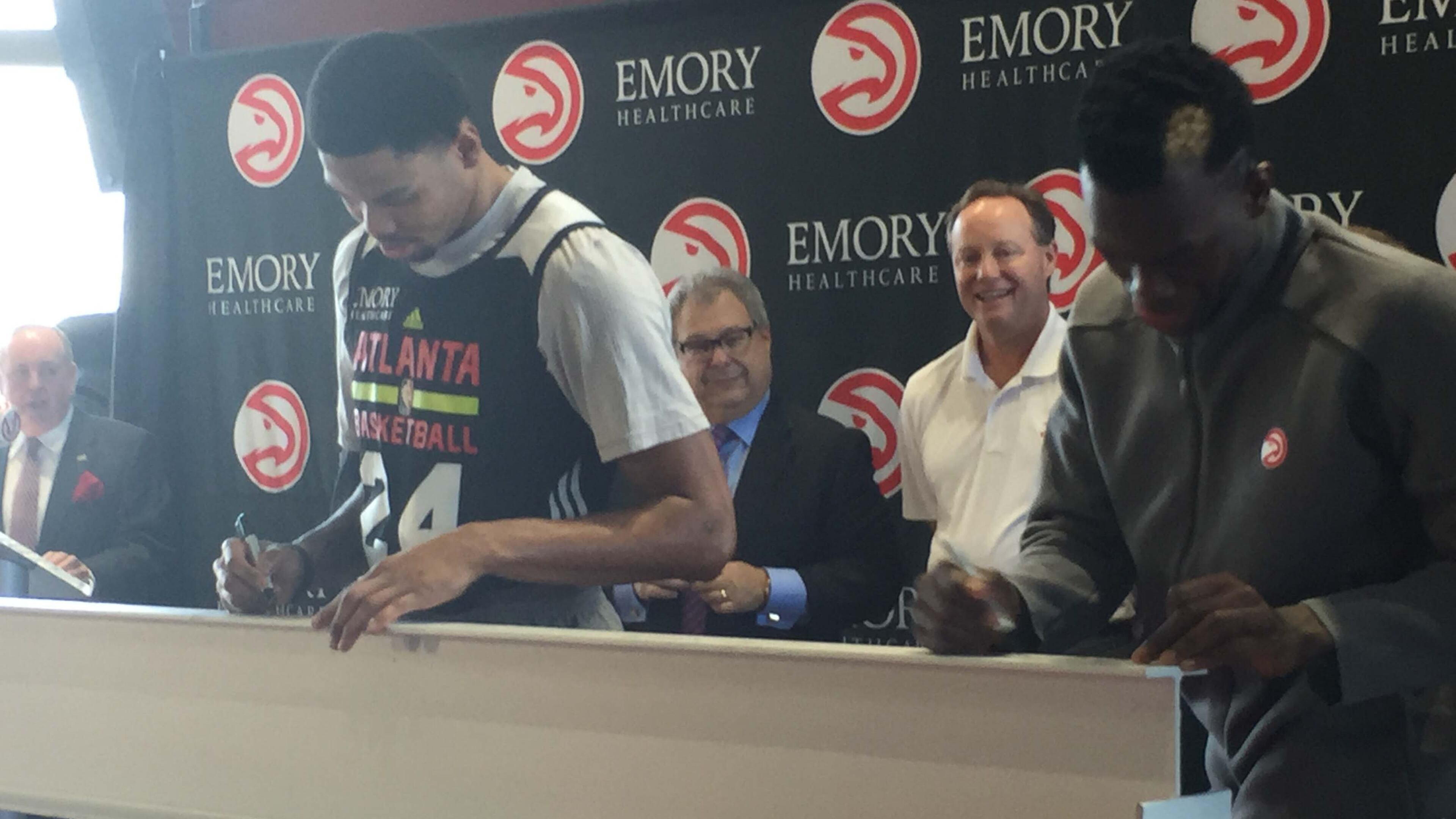 Kent Bazemore (left) and Dennis Schroder sign a beam that will be used in the construction of the team’s new practice facility. Photo by Chris Vivlamore