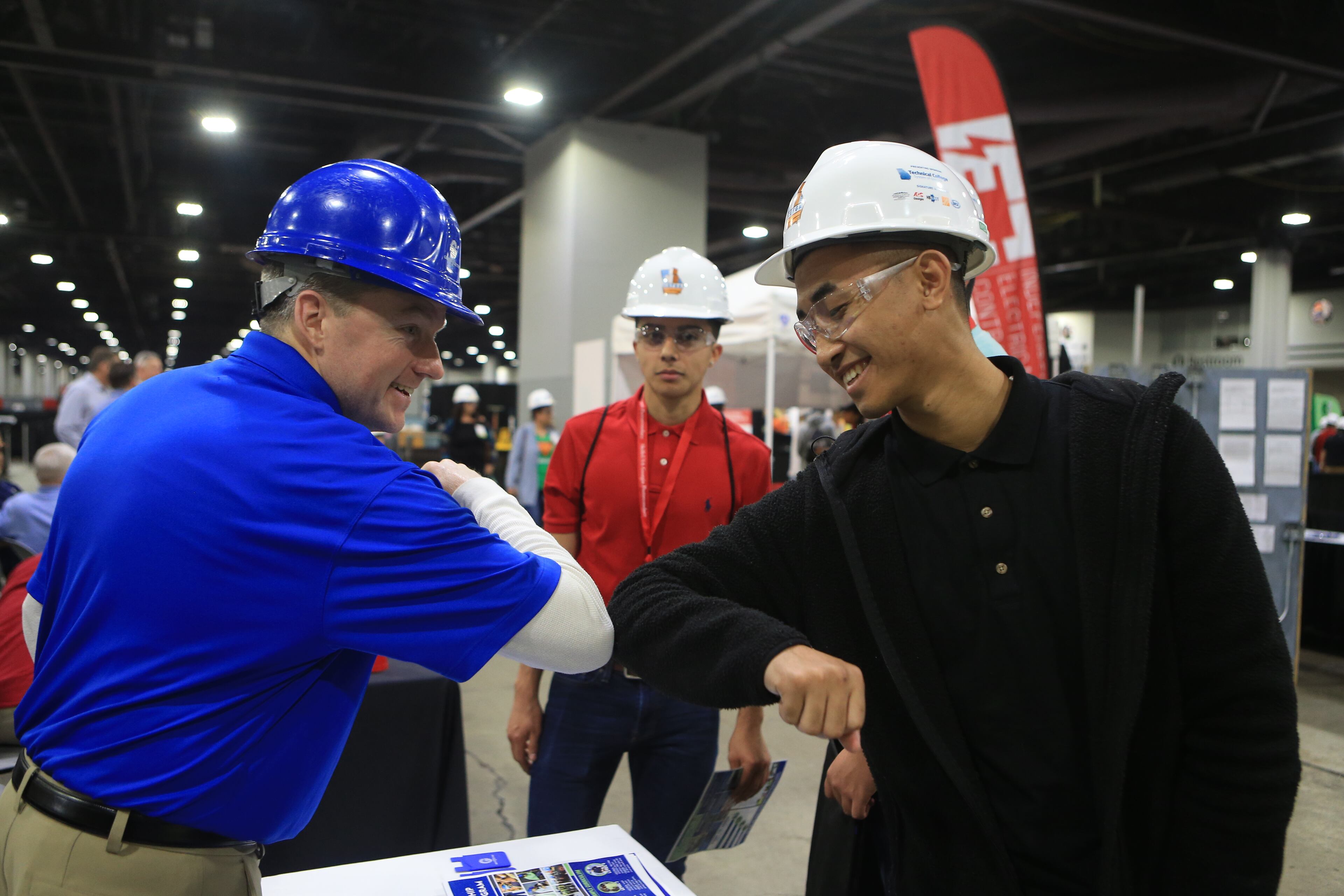 David Shea (left) and Brian Castillo (right) touch elbows during the Construction Education Foundation of Georgia (CEFGA) career expo on Thursday, March 12, 2020, at the World Congress Center in Atlanta. This year, additional safety measures were implemented, including mandatory hard hats and incremental wipe downs. (Christina Matacotta, for The Atlanta Journal-Constitution).