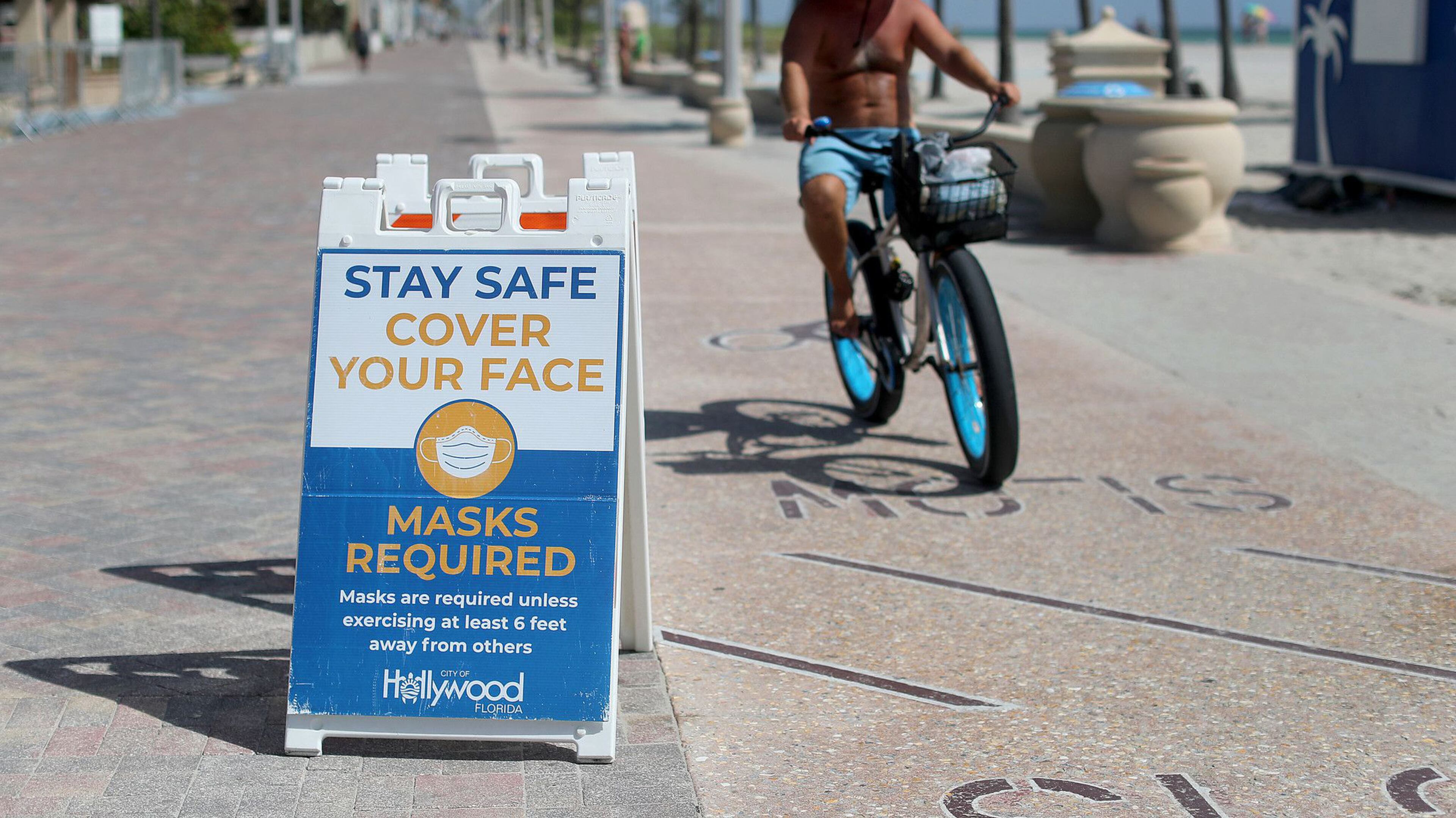 Signs posted along the broadwalk on the beach in Hollywood Florida advocate for people to wear a mask unless exercising 6 feet away from others in September 2020. (Mike Stocker/South Florida Sun Sentinel/TNS)