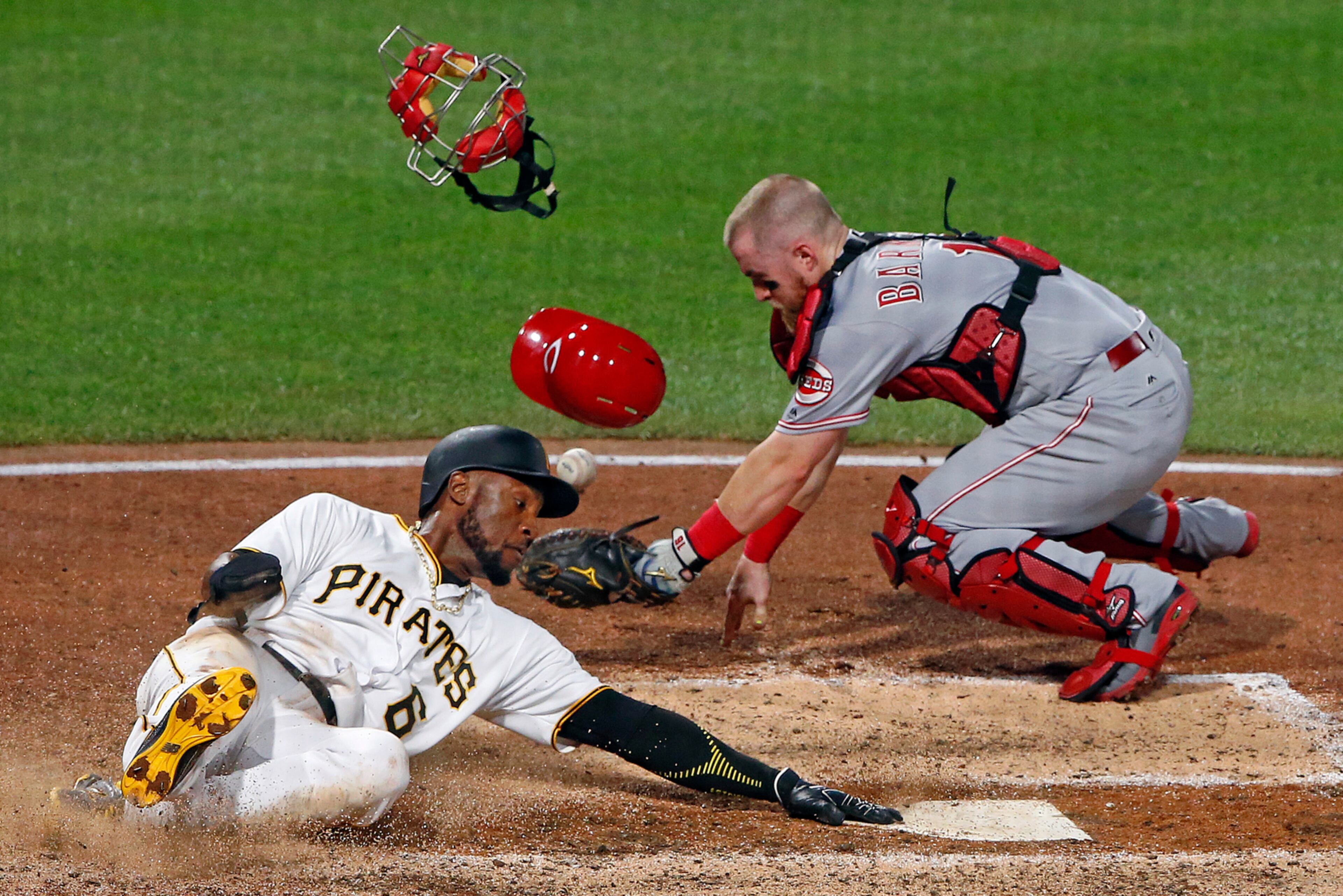 Cincinnati Reds catcher Tucker Barnhart drops the ball after tagging Pittsburgh Pirates' Starling Marte (6), who touches the plate to score the sixth inning of a baseball game in Pittsburgh, Wednesday, Aug. 2, 2017. (AP Photo/Gene J. Puskar)