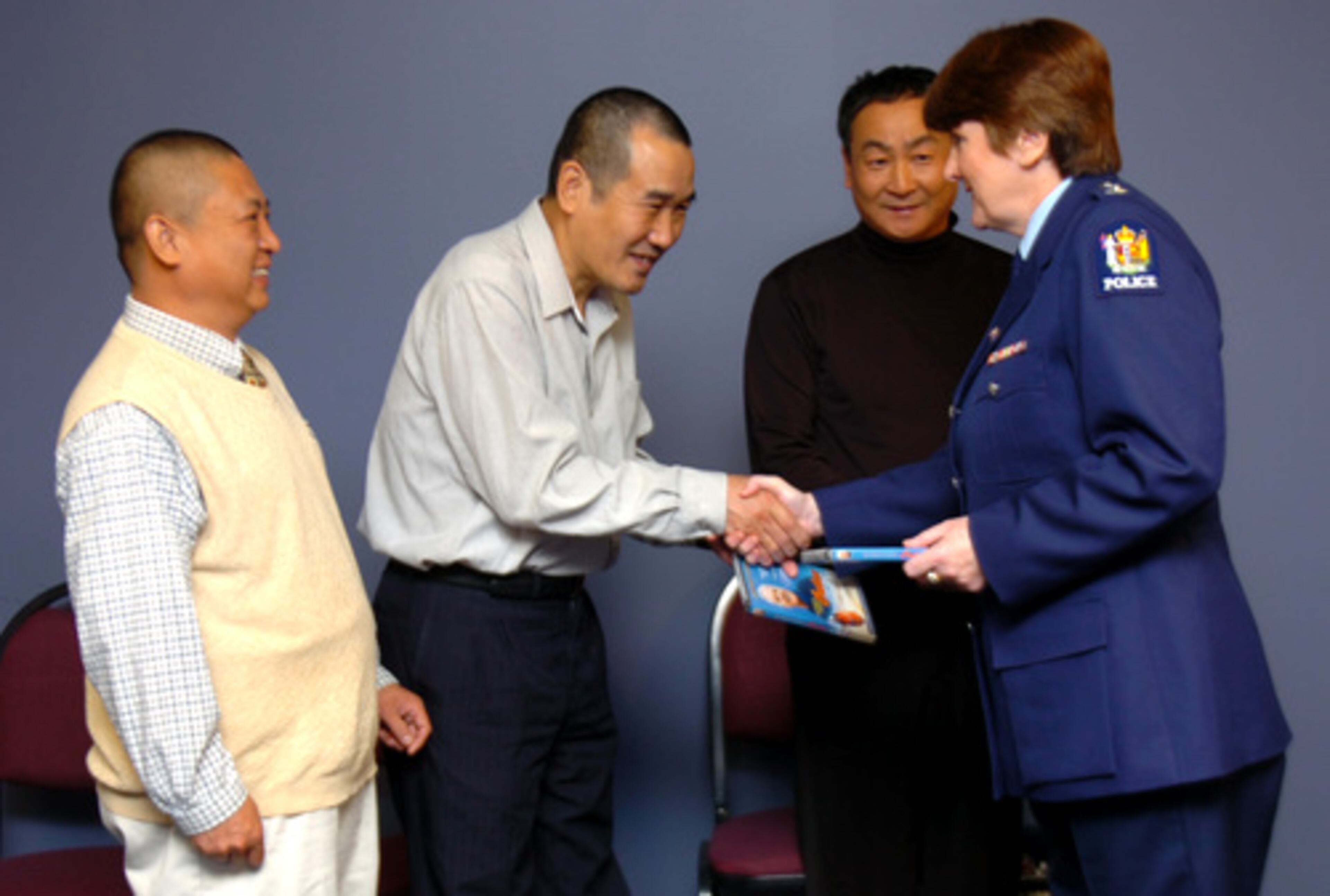 Superintendent Sandra Manderson (right) of the New Zealand Embassy in Washington presented the check to (from left) Gui Sen Wu, Xin Boa Li, and Shun Li Dong. New Zealand had offered the reward money.