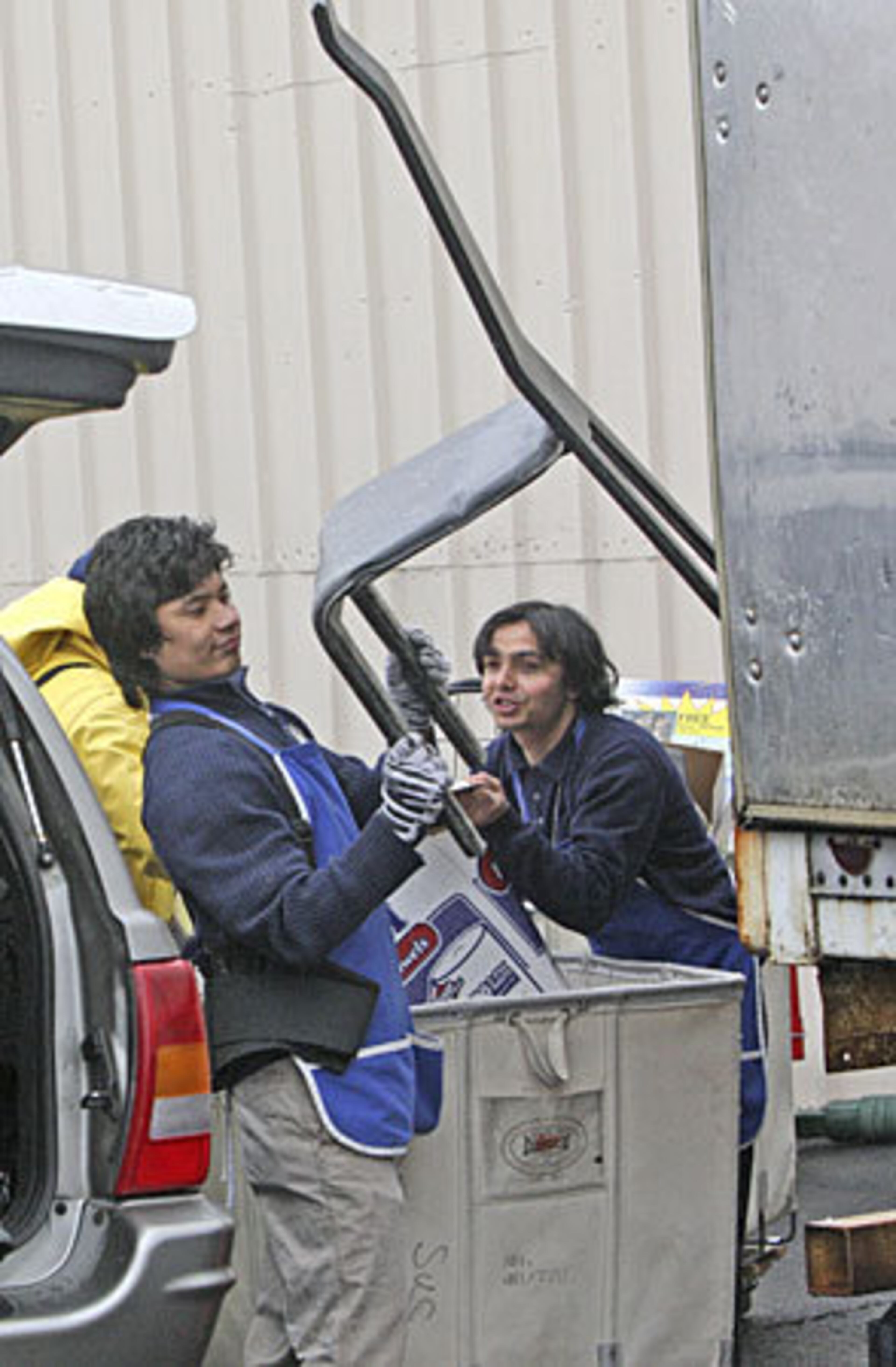 Goodwill employees (from left) Rai Ratan and Chandra Dahal load donated chairs.