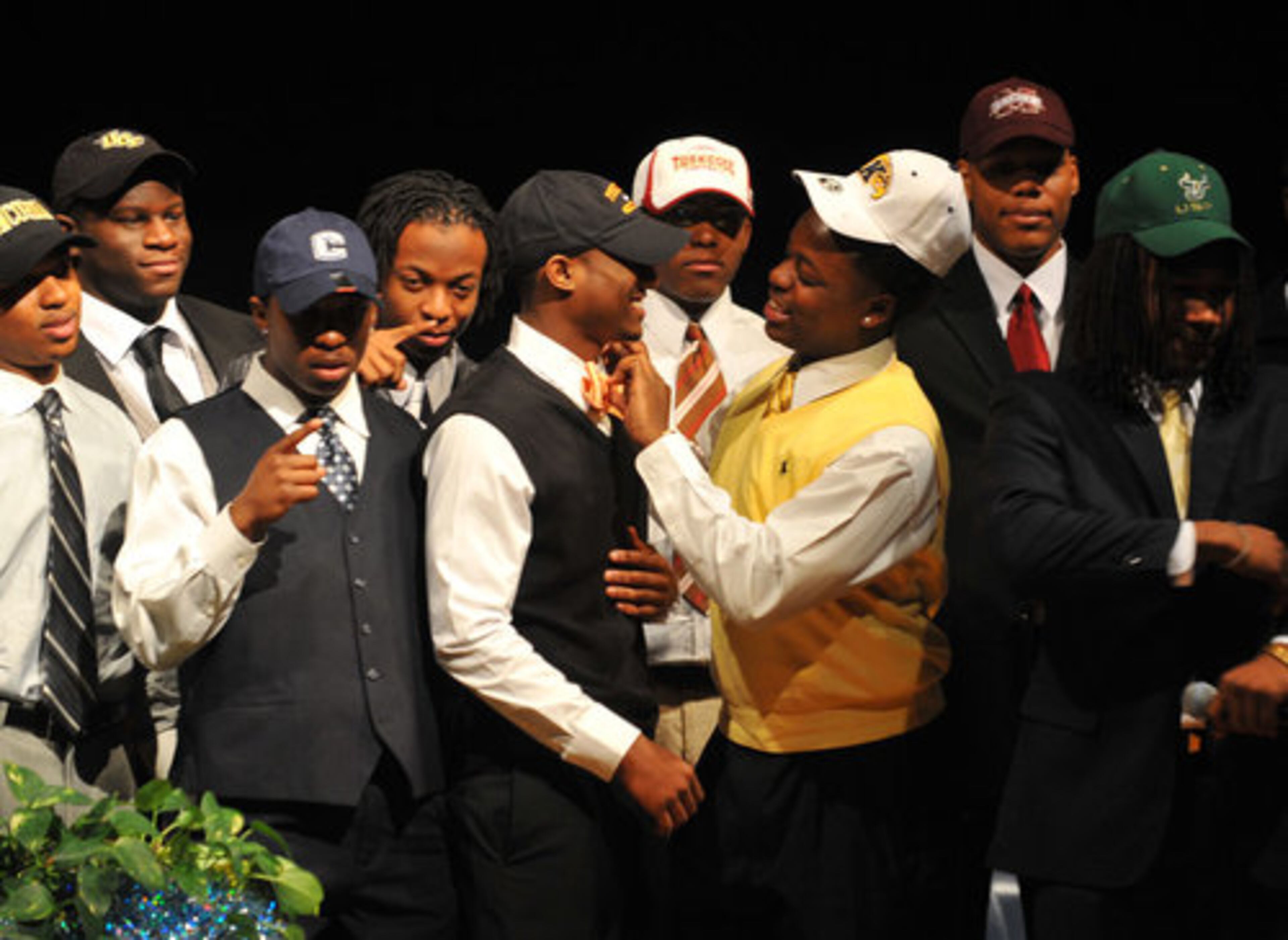 Erie Dulin (left), who announced he will play for Tusculum College in Tennessee gets help adjusting his tie from teammate Jordan Tarver, who will play for Kent State, during a group photo at Stephenson High School.