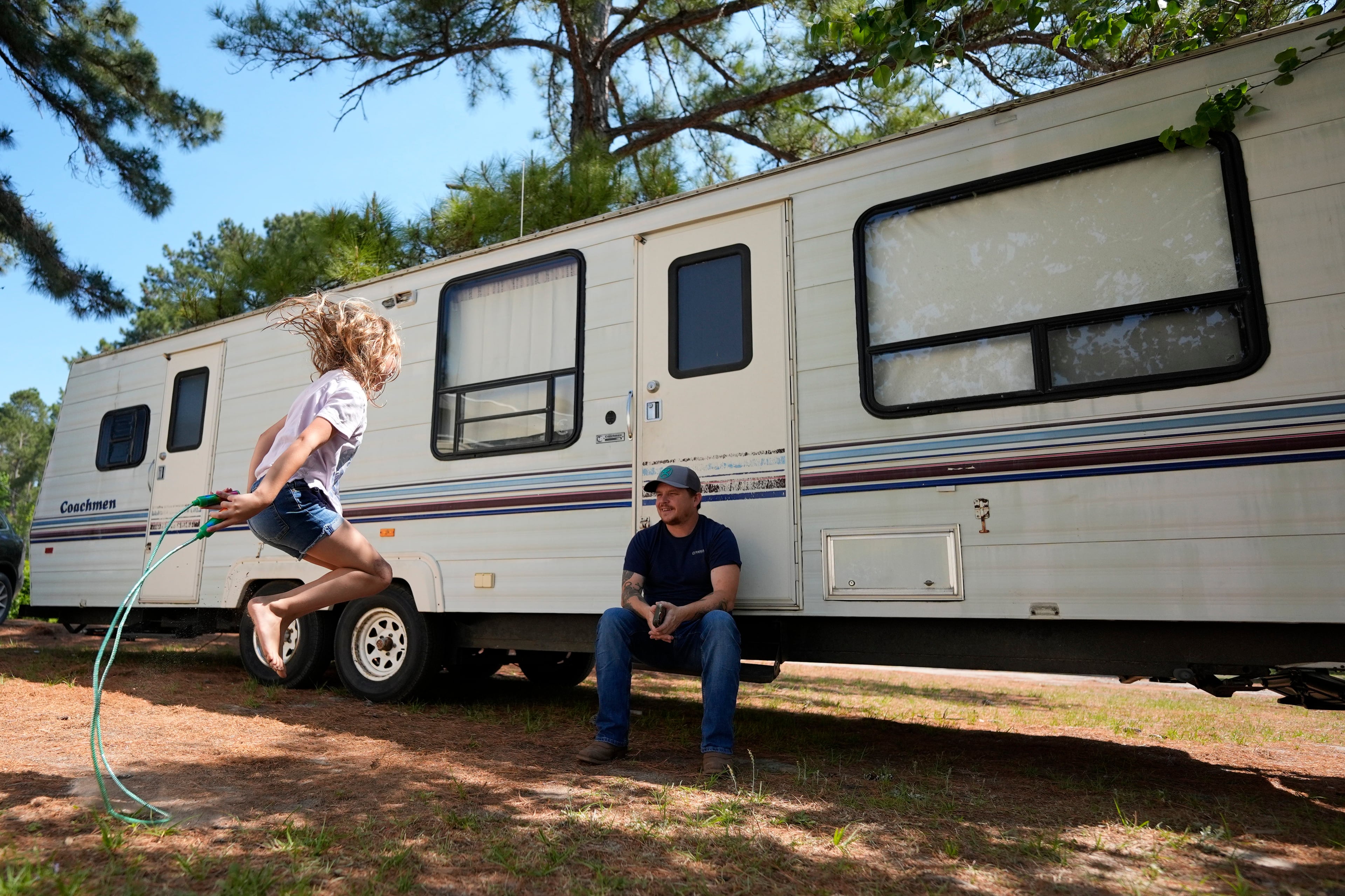 Annabelle Enke plays outside a camper Friday as Michael Gibson looks on in Nahunta, Georgia, after the Enke family lost their home in the Brantley Highway 82 fire earlier this week. (Mike Stewart/AP)