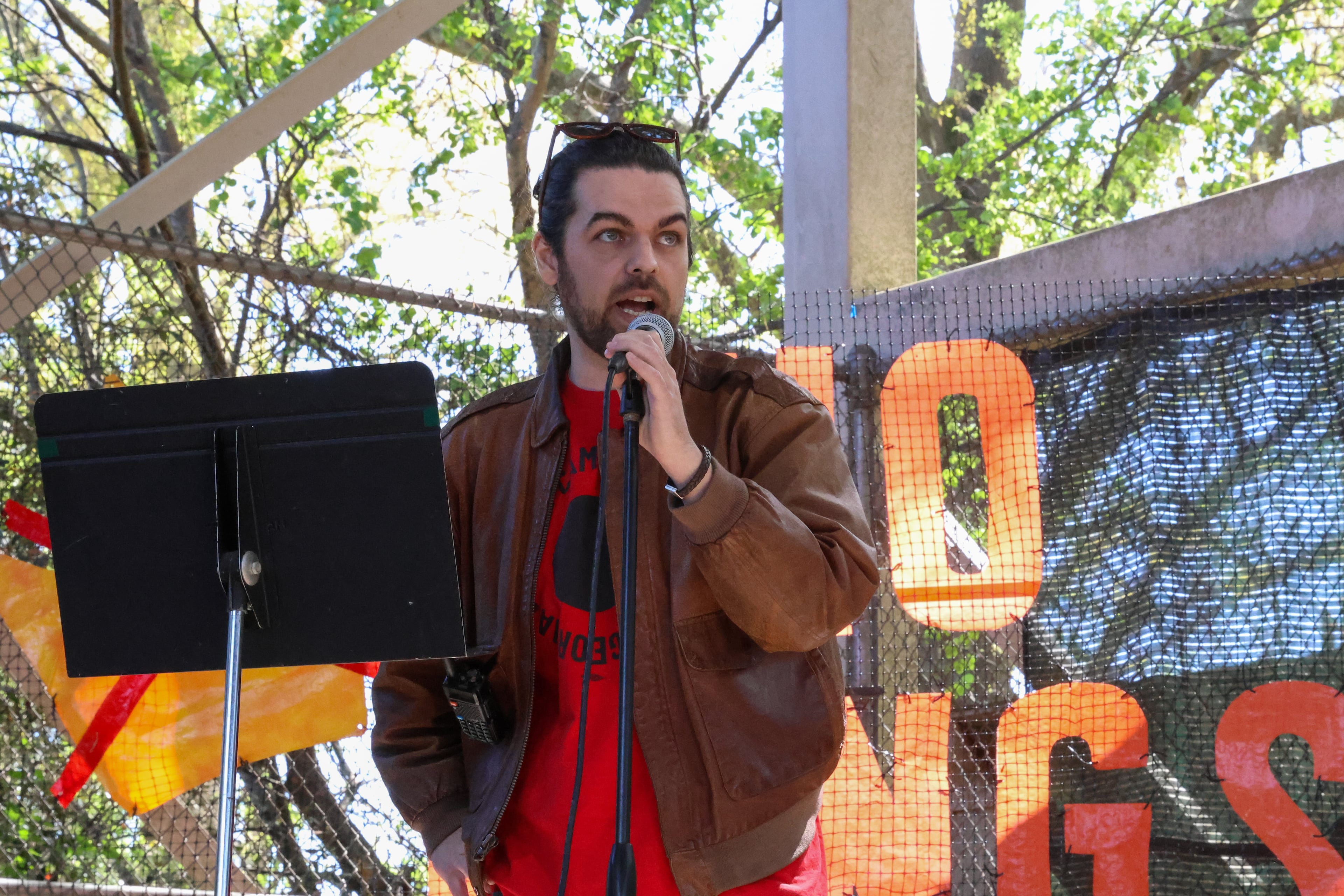 Bryant Barnes, an organizer with United Campus Workers of Georgia, speaks at a rally at Bishop Park in Athens on Saturday, March 28, 2026. Protesters gathered in 10 different locations around Georgia’s Congressional District 10, leading up to a “Democracy Fair” at Bishop Park as part of a nationwide day of “No Kings” demonstrations. Organizers estimate that a few thousand people participated, many of them first-time protesters. (C.J. Bartunek for the AJC)