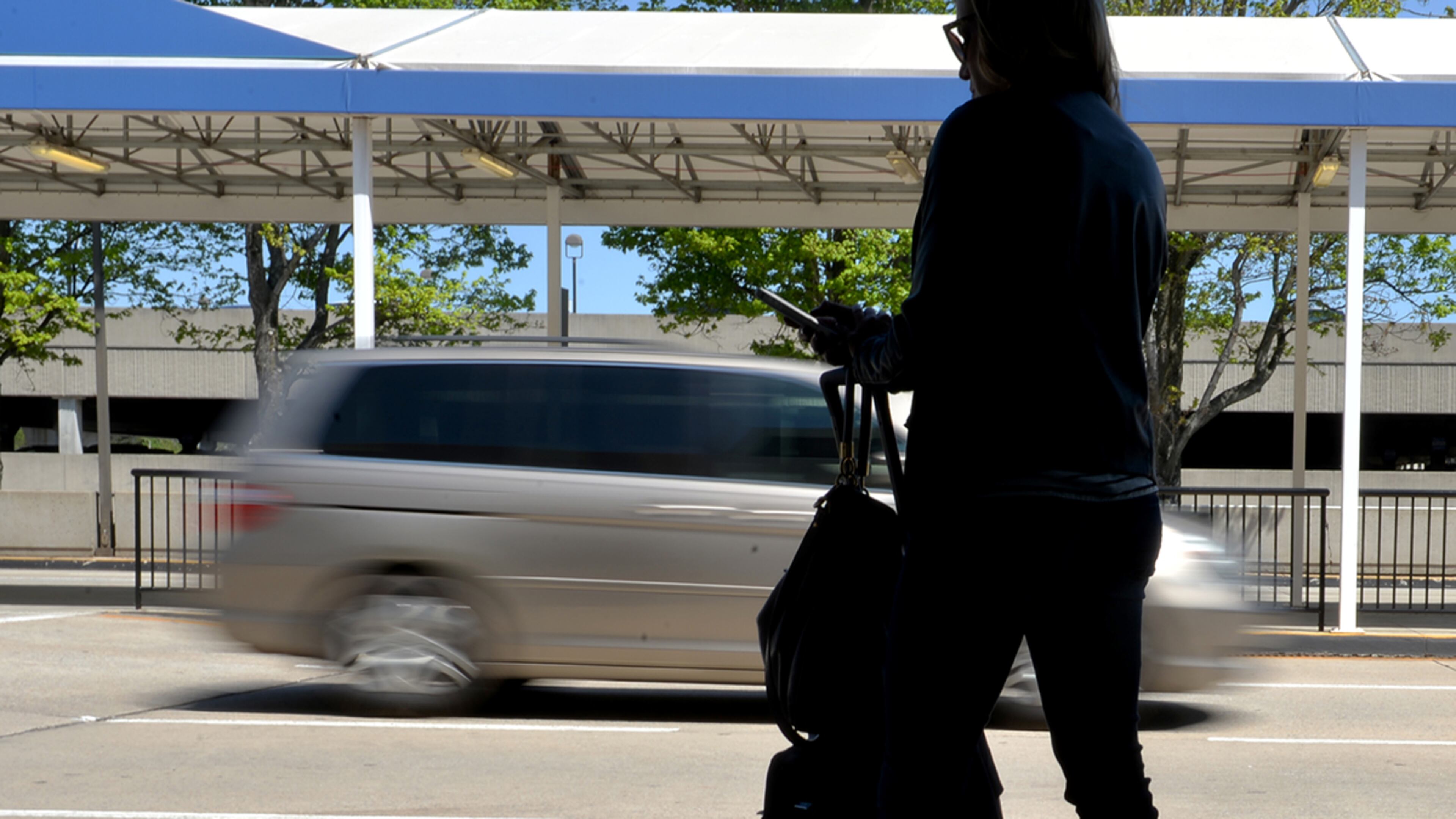 An arriving passenger waits for a ride at Hartsfield Jackson International Airport. According to a recent Morgan Stanley report, ride-sharing services could disrupt transit planning as much as they're already disrupting taxi services. (Brant Sanderlin / AJC file)