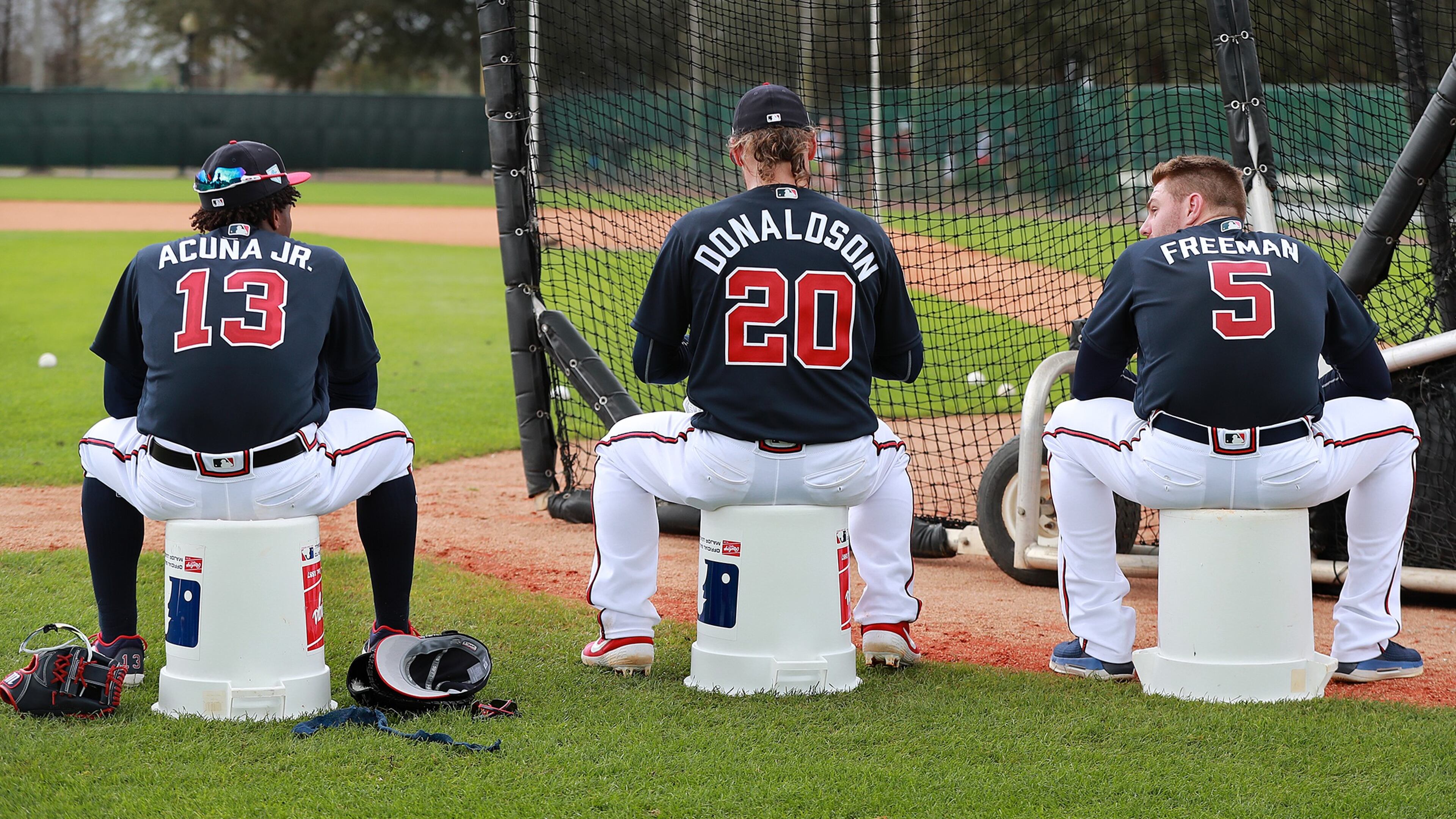 Atlanta Braves players Ronald Acuna Jr. (from left), Josh Donaldson, and Freddie Freeman use empty baseball buckets to sit on while waiting their turn to bat during the first full squad workout at spring training in the ESPN Wide World of Sports Complex on Thursday, Feb. 21, 2019, in Lake Buena Vista. Curtis Compton/ccompton@ajc.com
