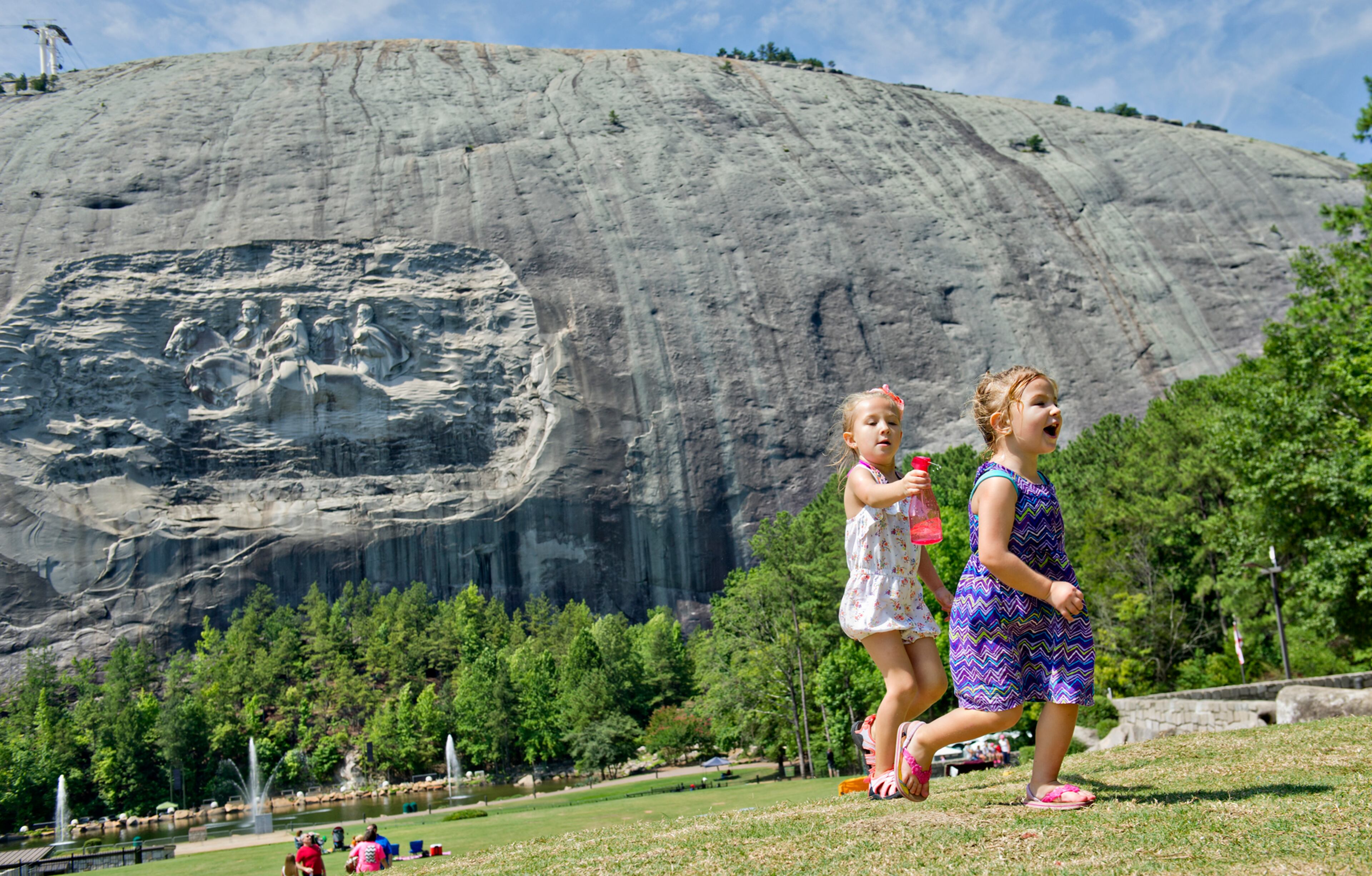 Gabraila Bartlett (left) chases after her sister Caroline with a water bottle on the main lawn at Stone Mountain Park during the Fantastic Fourth celebration weekend on Saturday, July 5, 2014.