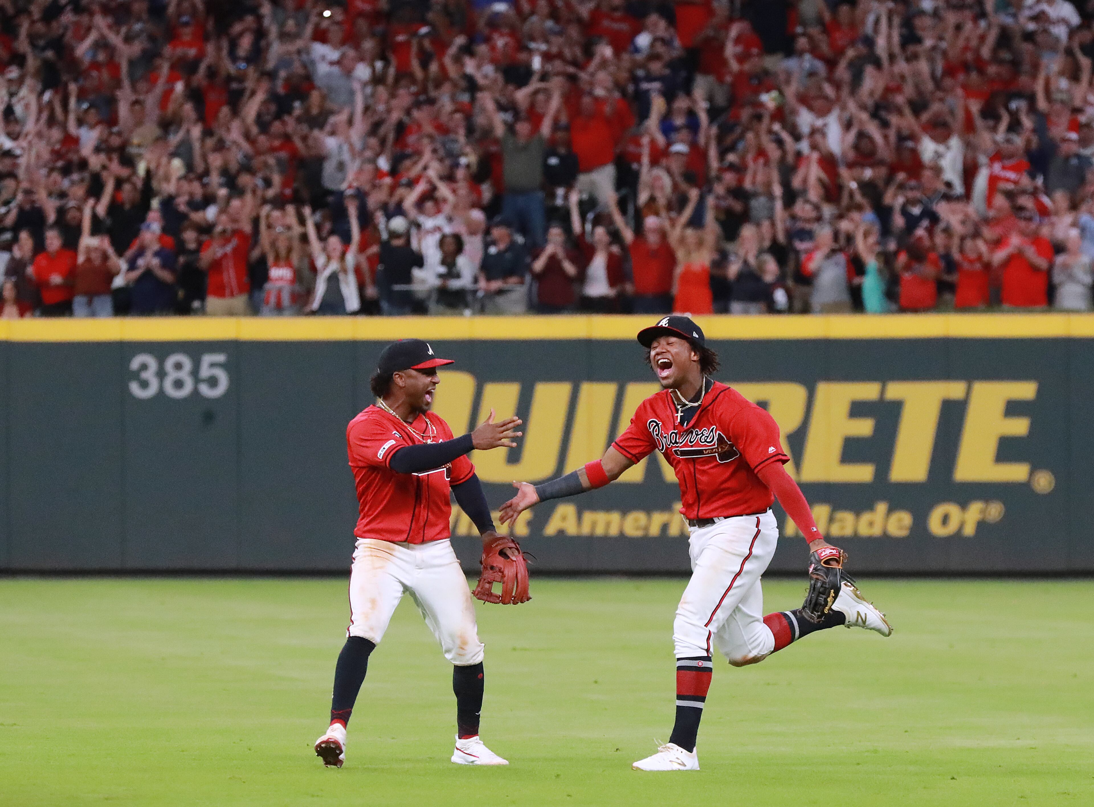 Ozzie Albies (left), Ronald Acuna (right) and Braves fans celebrate after Acuna Jr. caught a fly ball for the last out. Curtis Compton/ccompton@ajc.com