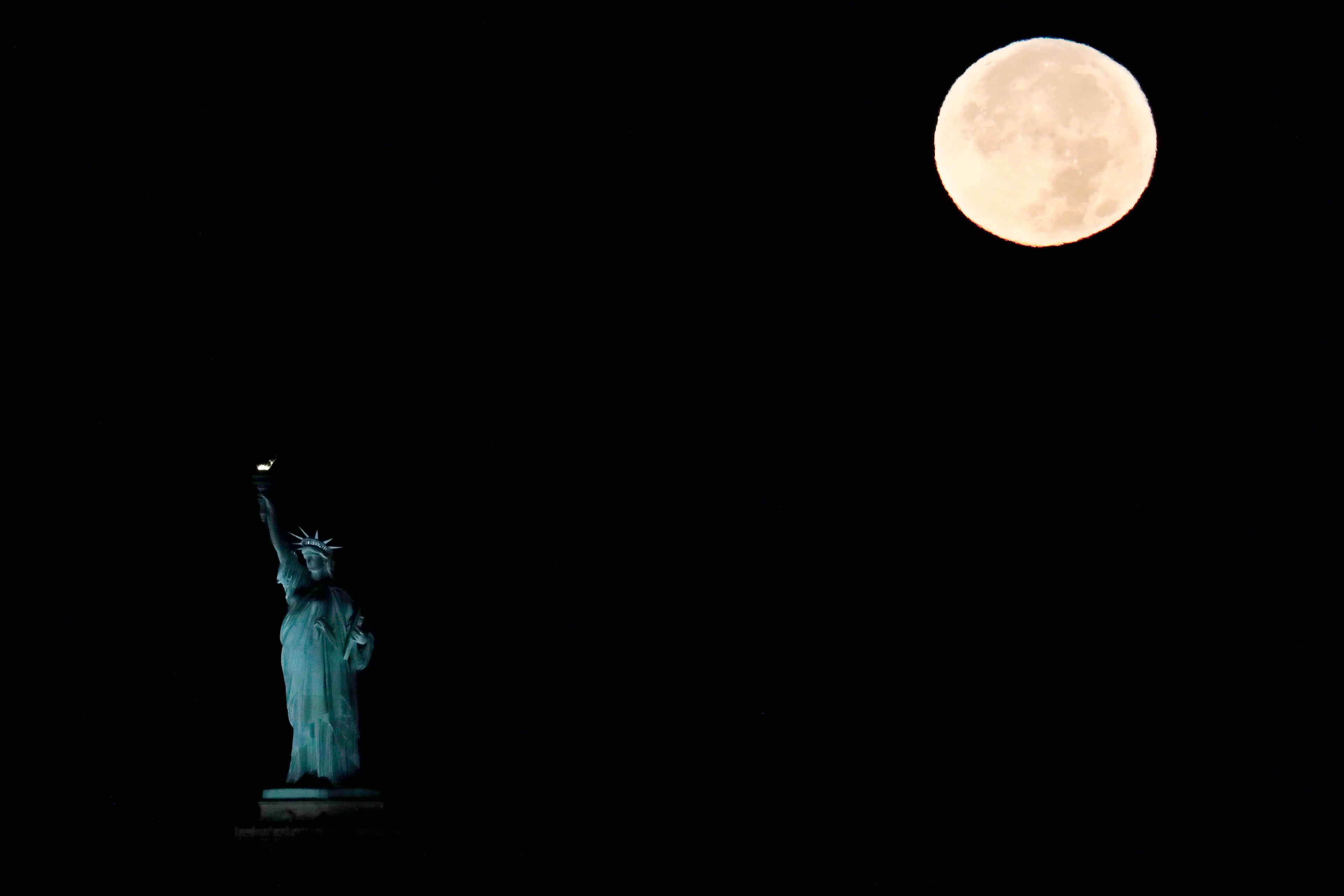 The supermoon sets behind the Statue of Liberty, Monday, Nov. 14, 2016, in New York. Monday's supermoon, a phenomenon that happens when the moon makes a close pass at the earth, is the closest to earth since 1948. (AP Photo/Julio Cortez)