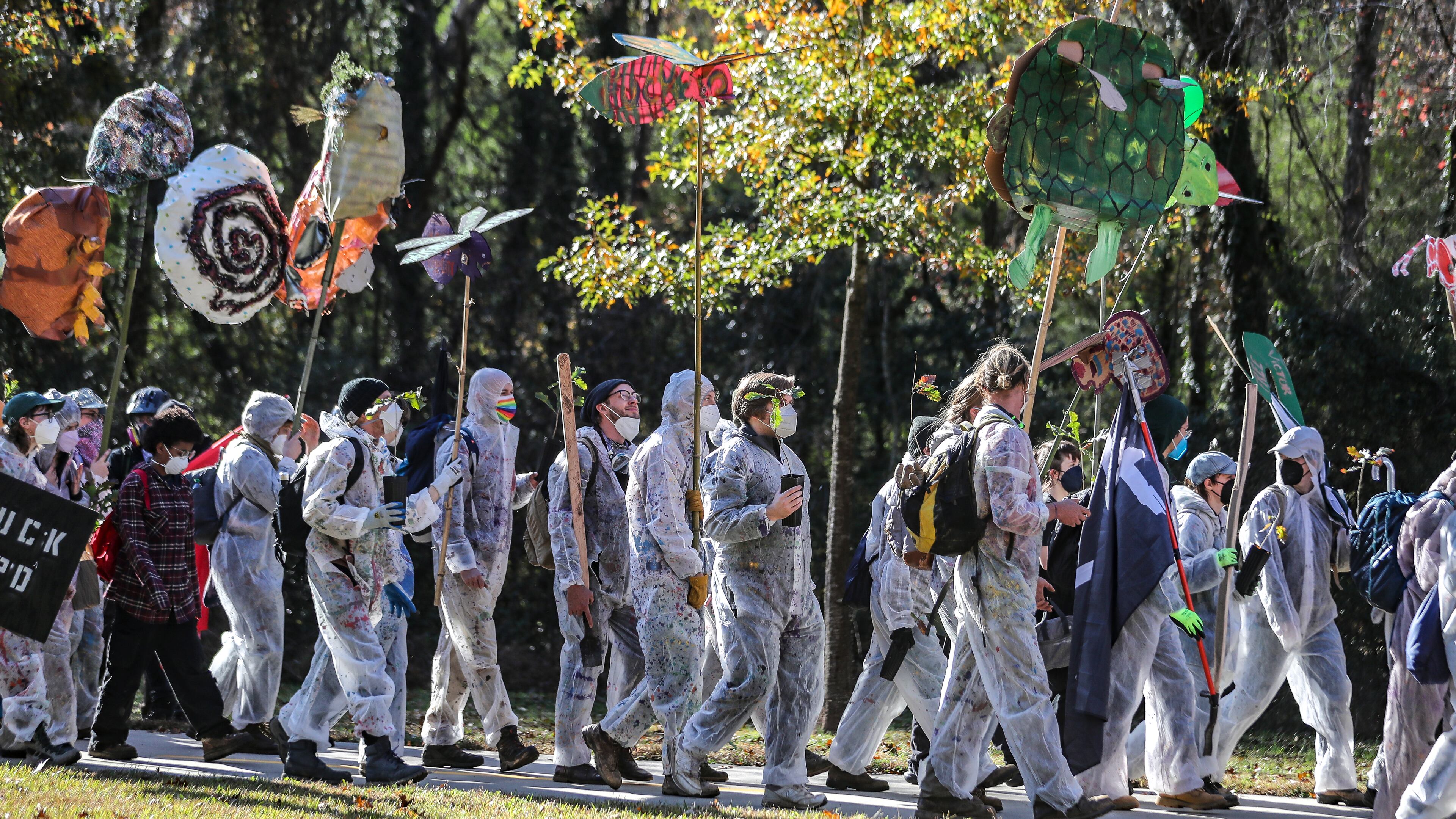 Protesters head through the neighborhoods to the showdown with police on Constitution Road on Nov. 13. After a weekend of protest training, opponents of Atlanta's public safety training center began marching Monday morning from Gresham Park Recreation Center to the site where the $90 million facility is under construction in what organizers are calling a non-violent 'Day of Action.' A few hundred people participated in the march, most wearing masks and many donned in plastic painters suits. City officials say the new center is necessary to provide world-class training to its officers and firefighters, which are currently using outdated facilities. Opponents say it will be used to further militarize police and construction will destroy swaths of one of the largest urban forests in the country. (John Spink / John.Spink@ajc.com)